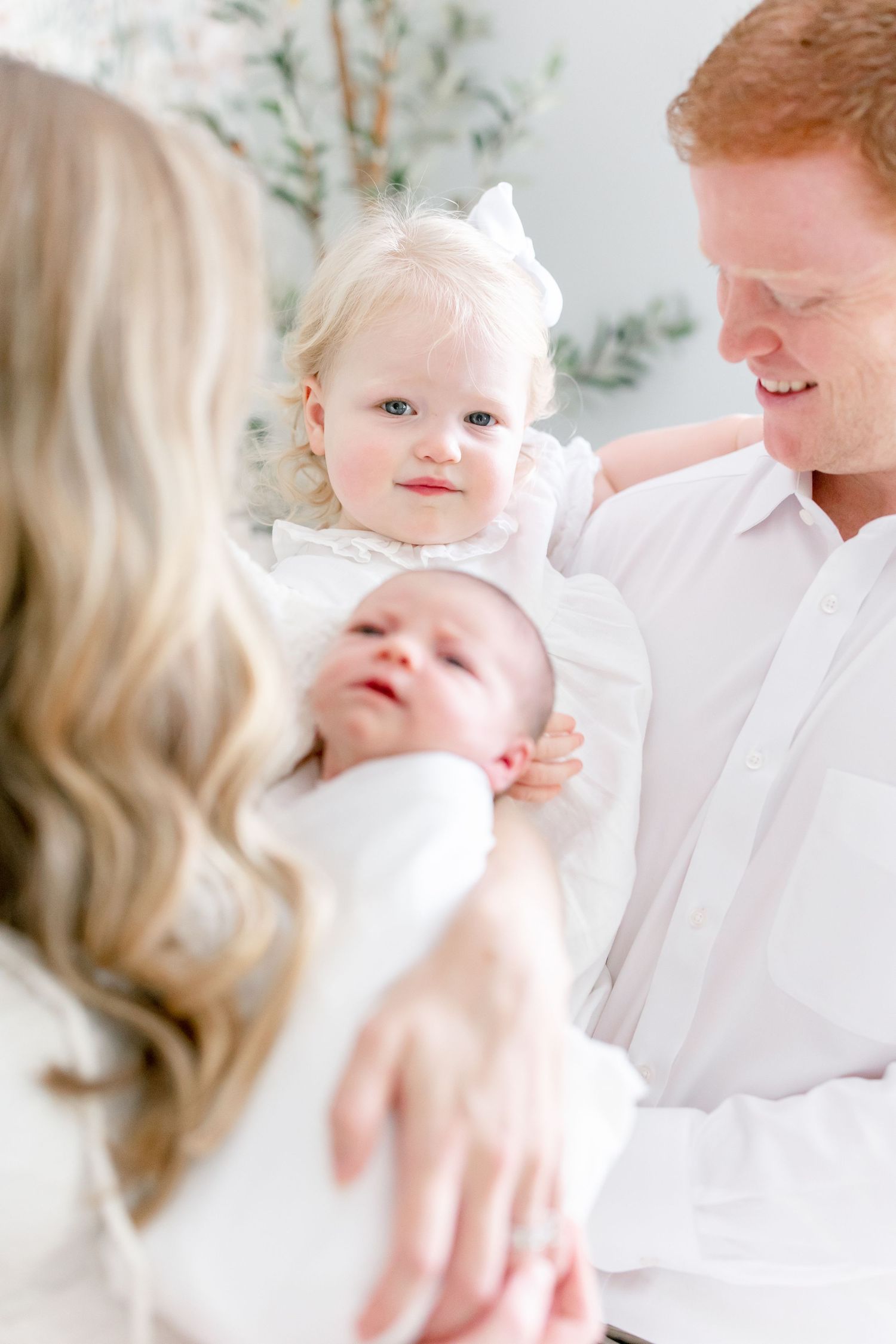 Family portraits showing intimate moments with baby in bright white setting.