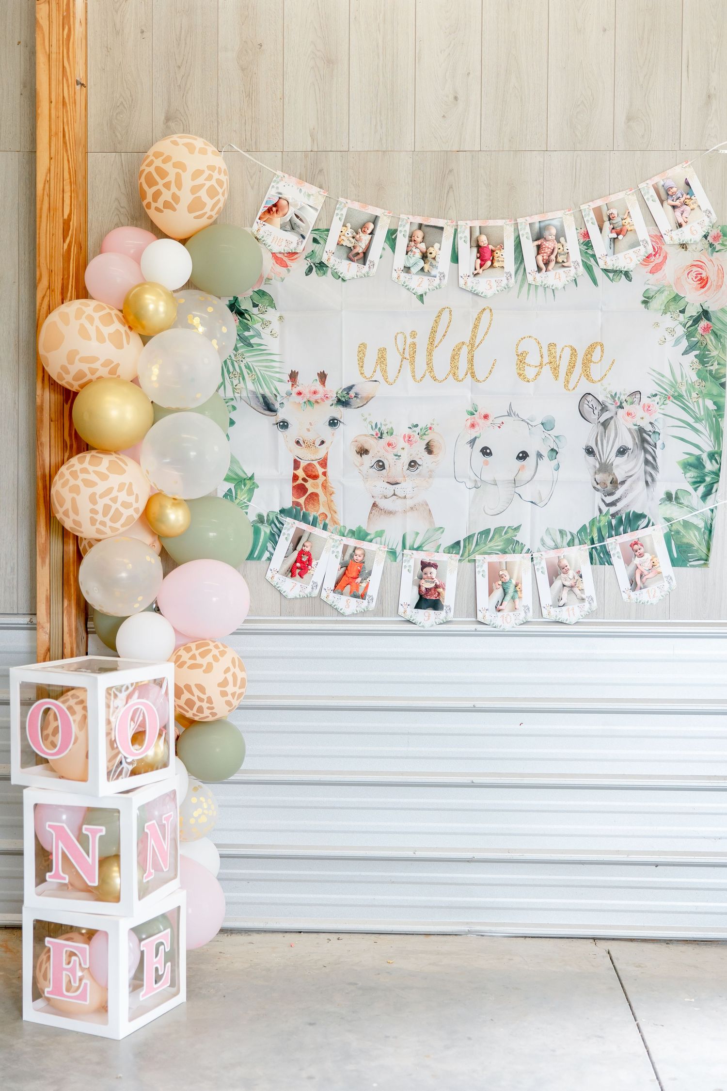 Safari-themed first birthday party backdrop with balloon arch and decorative photo display.