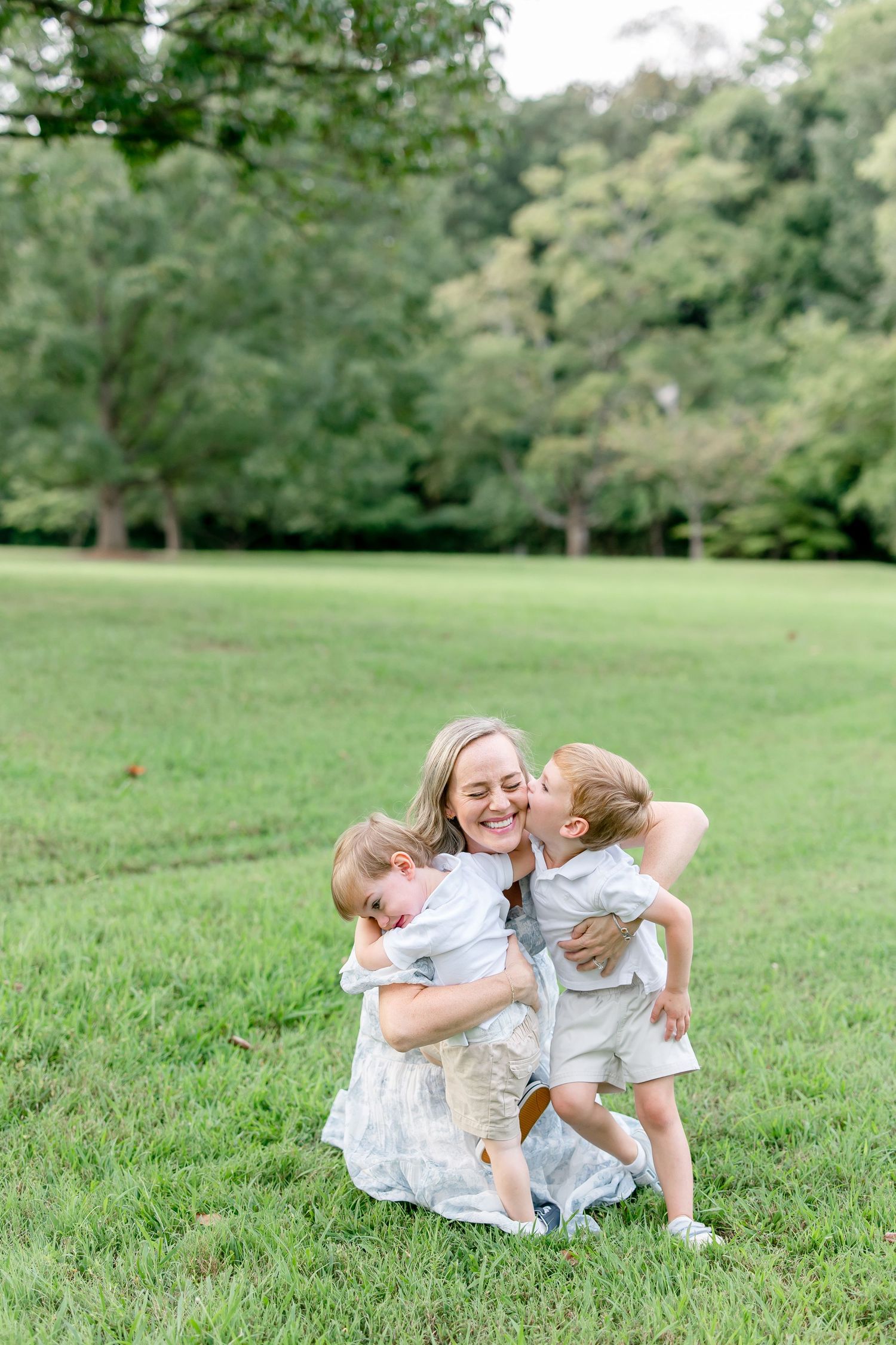 A playful moment captured of people lying on green grass during a sunny outdoor photo session.