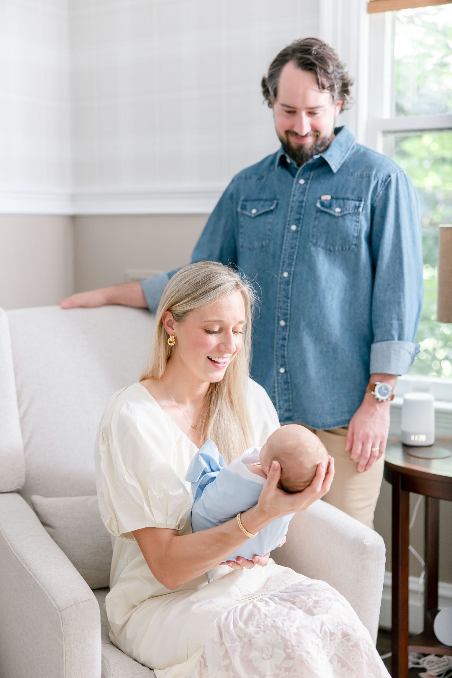 Intimate family moment in bright living room with white armchair and wooden accents.
