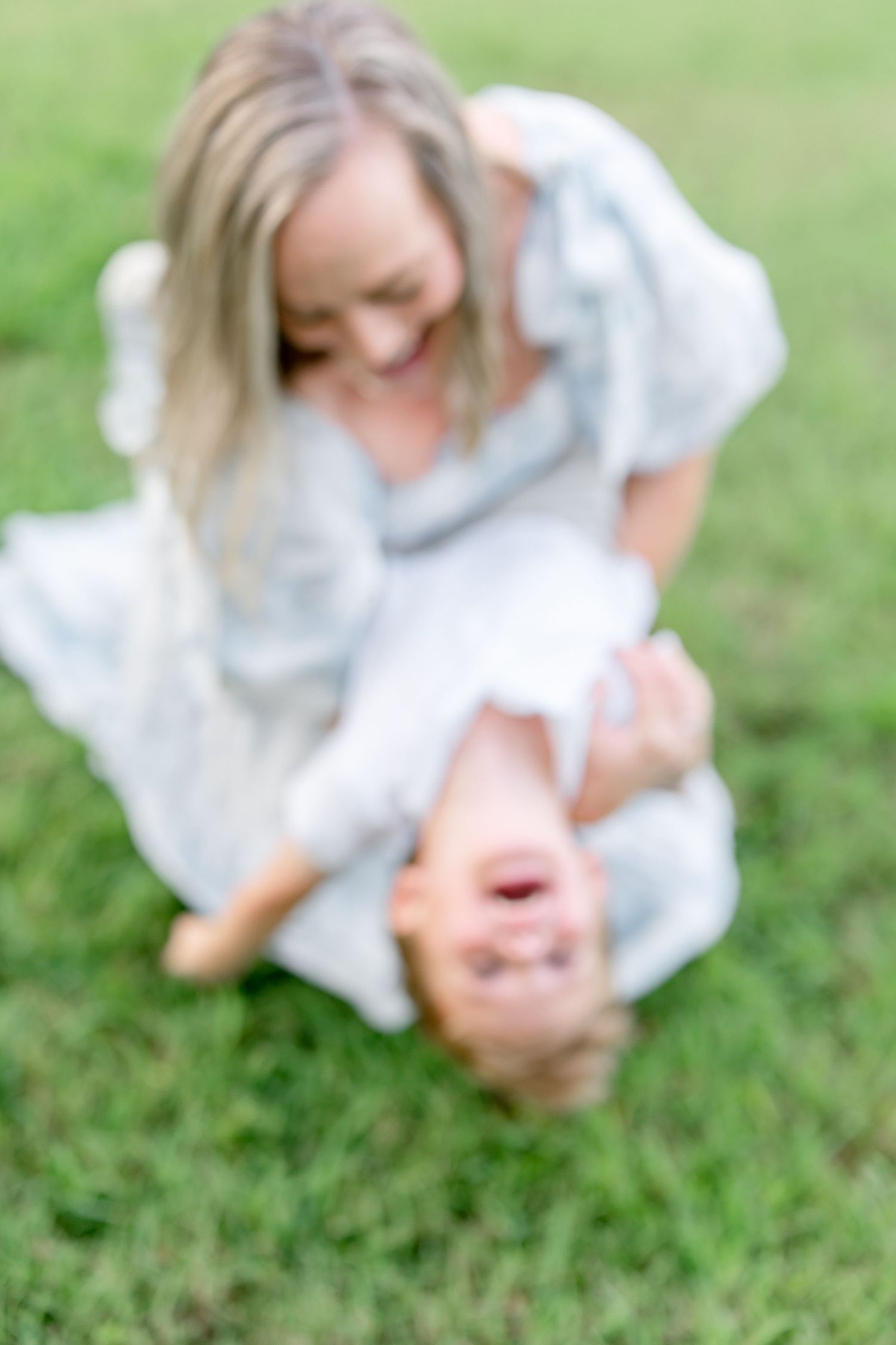 Blurred artistic photos showing movement and laughter during an outdoor family photoshoot on green grass.