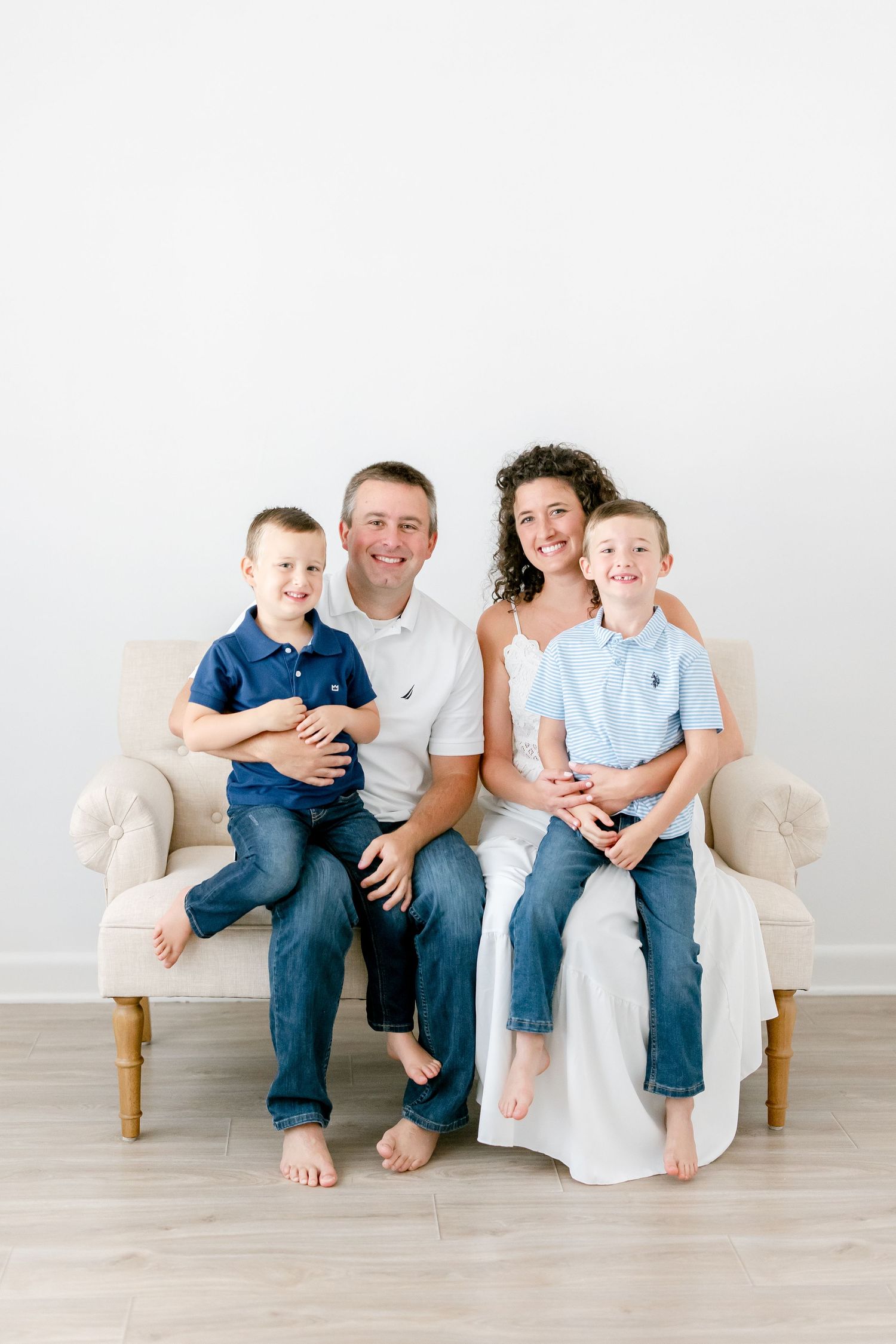 A loving family shares joyful moments together on a white couch against a neutral background.