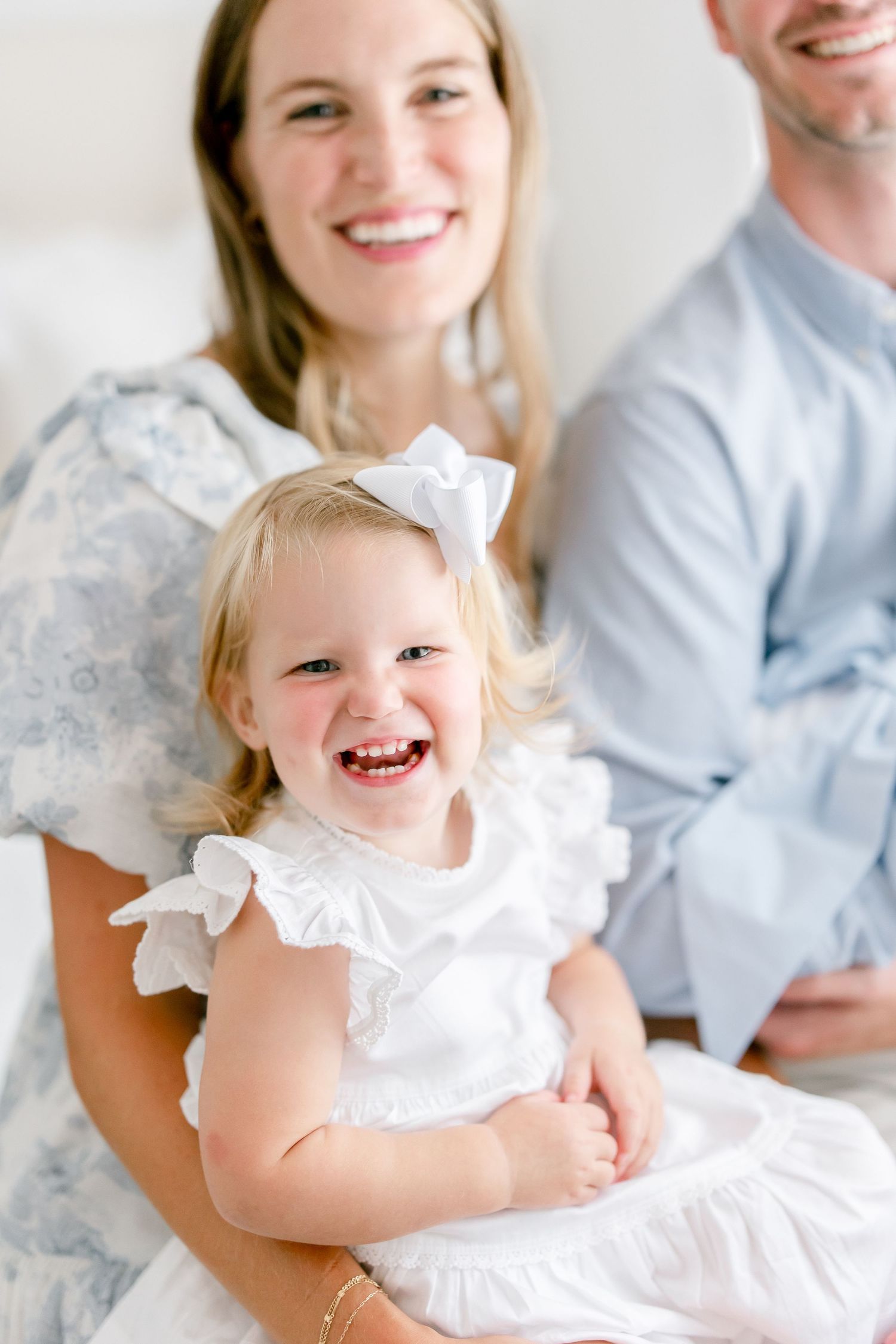 A heartwarming series of candid family portraits showing natural expressions while wearing coordinated white and light blue outfits.