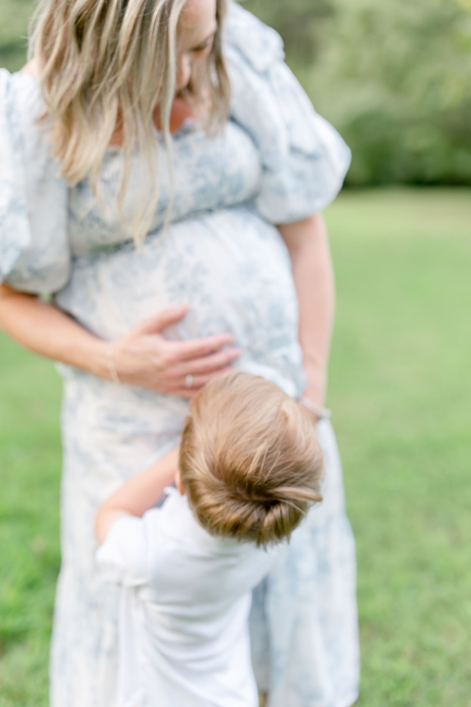 A series of connected photos showing a tender embrace between parent and child in a grassy outdoor setting.
