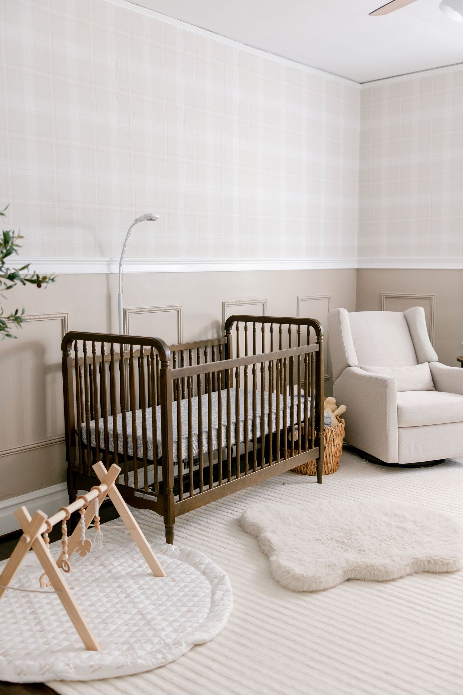 Minimalist nursery room with dark wood crib, white decor, and wooden rocking horse on round cream area rug.