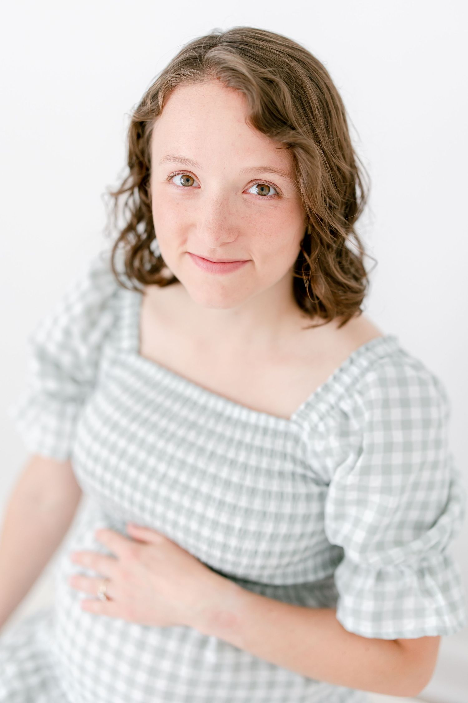 A person wearing a light blue gingham dress smiles and poses against a white backdrop in a collection of four photos.
