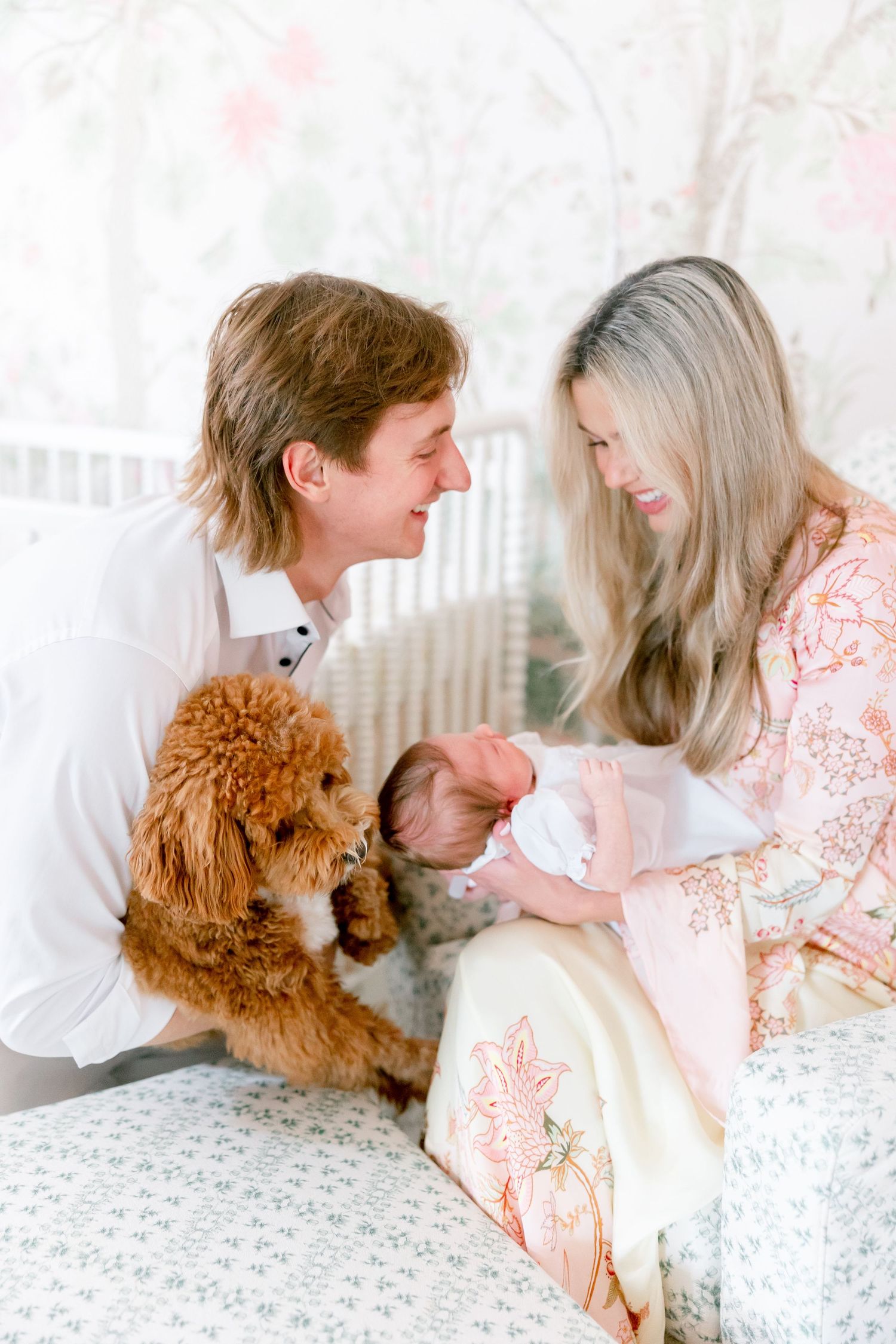 Couple lounging on white bedding with their fluffy brown poodle dog in romantic lifestyle photos.