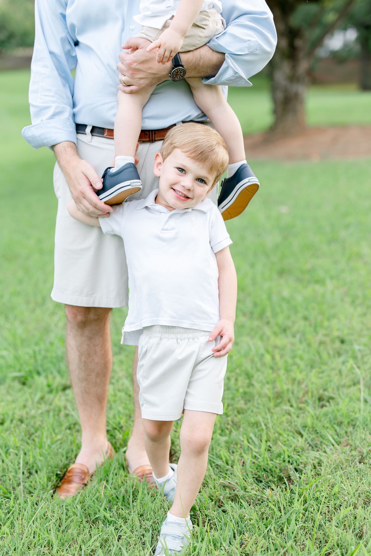 A close-up view shows family members wearing coordinated casual outfits while playing outdoors on grass.