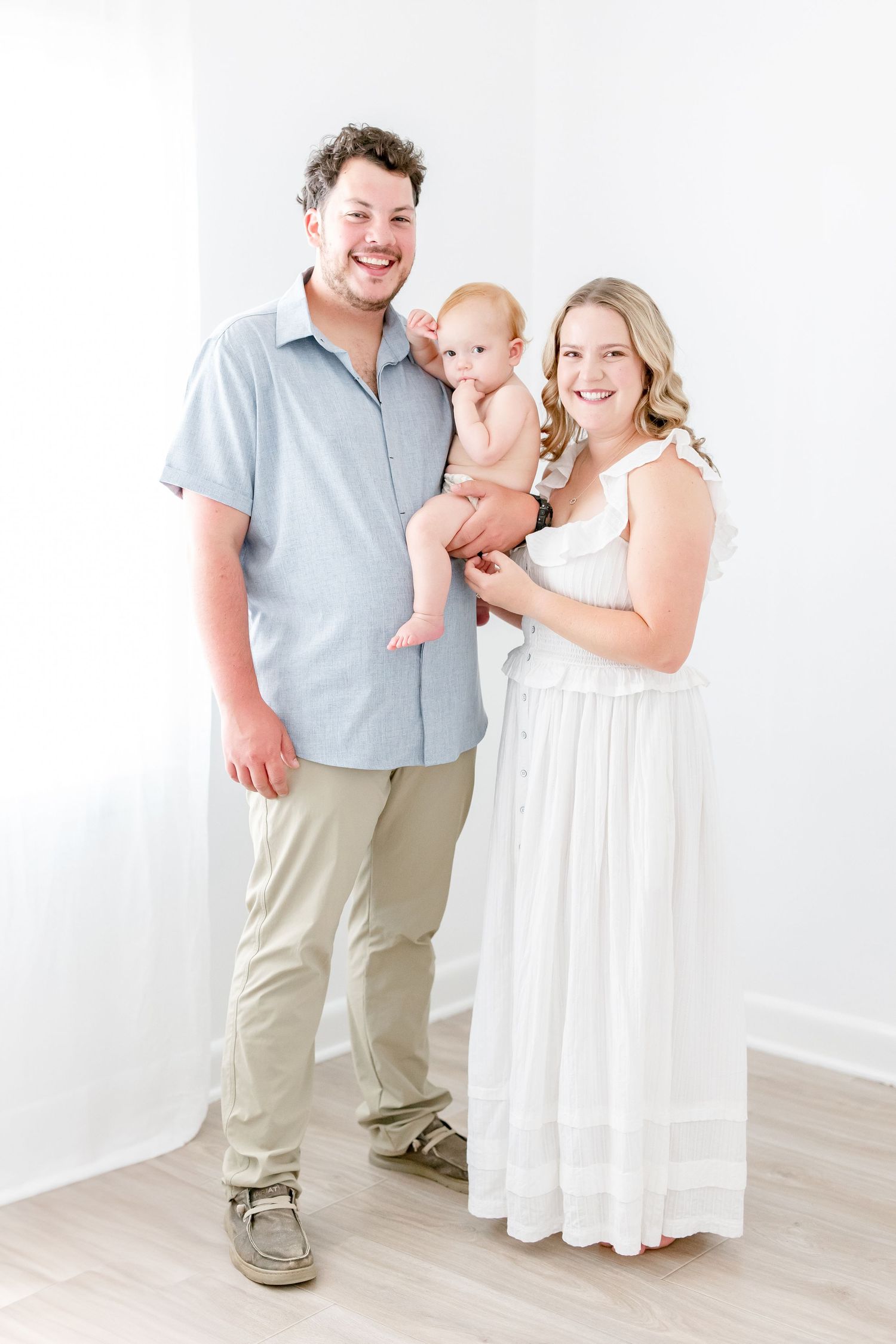 A family wearing white and blue outfits shares happy moments together in a bright studio setting.