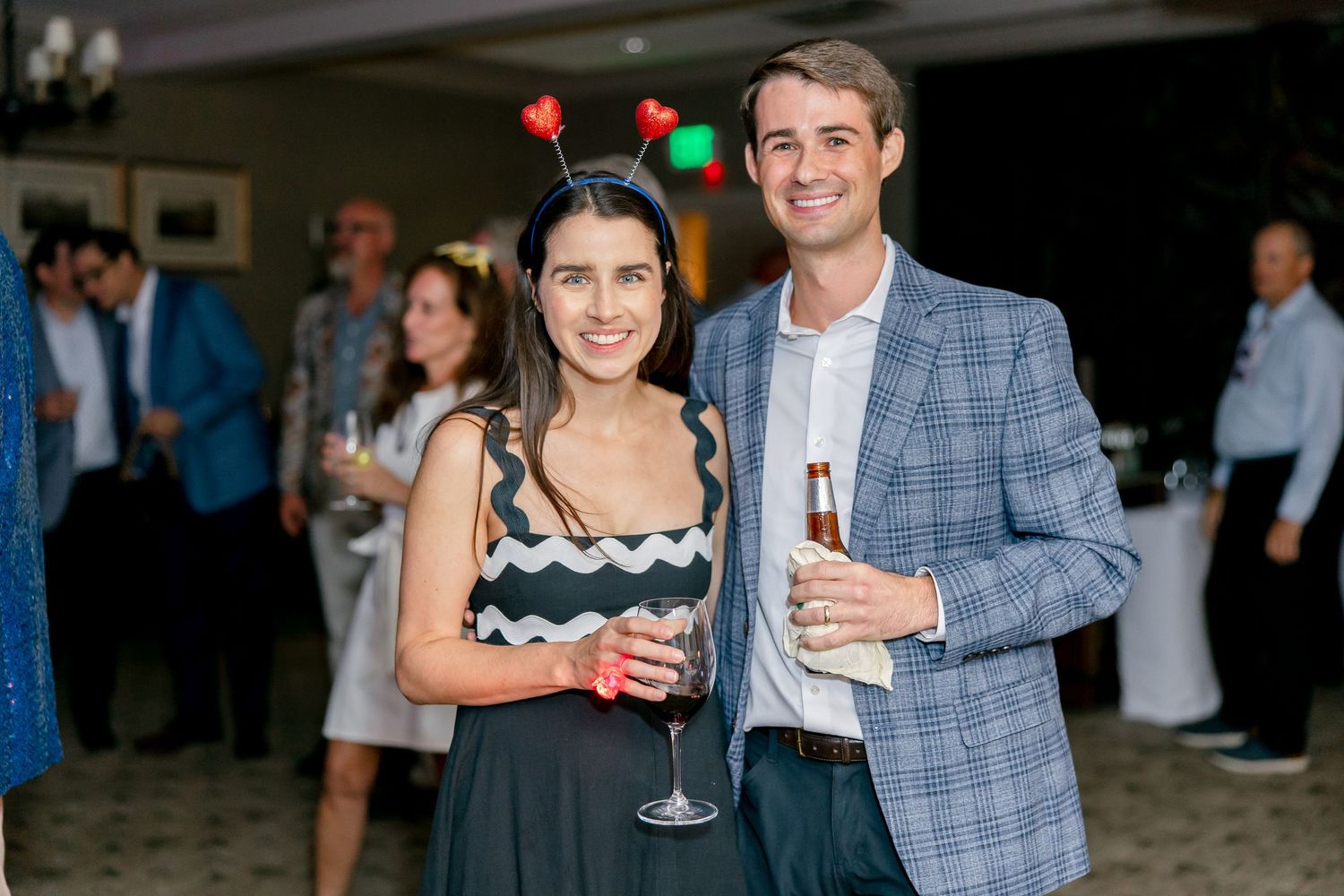 People enjoying drinks and socializing at an evening indoor event with dimmed lighting.