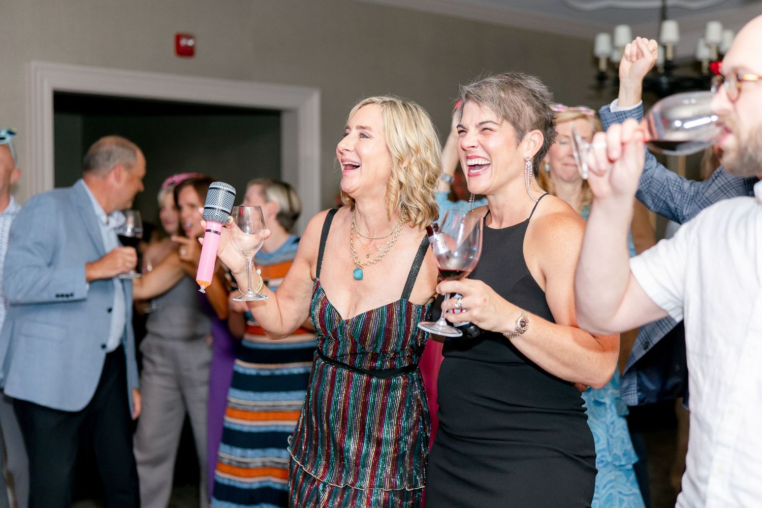 People dancing and celebrating at a lively reception venue with a crowd gathered on the dance floor.
