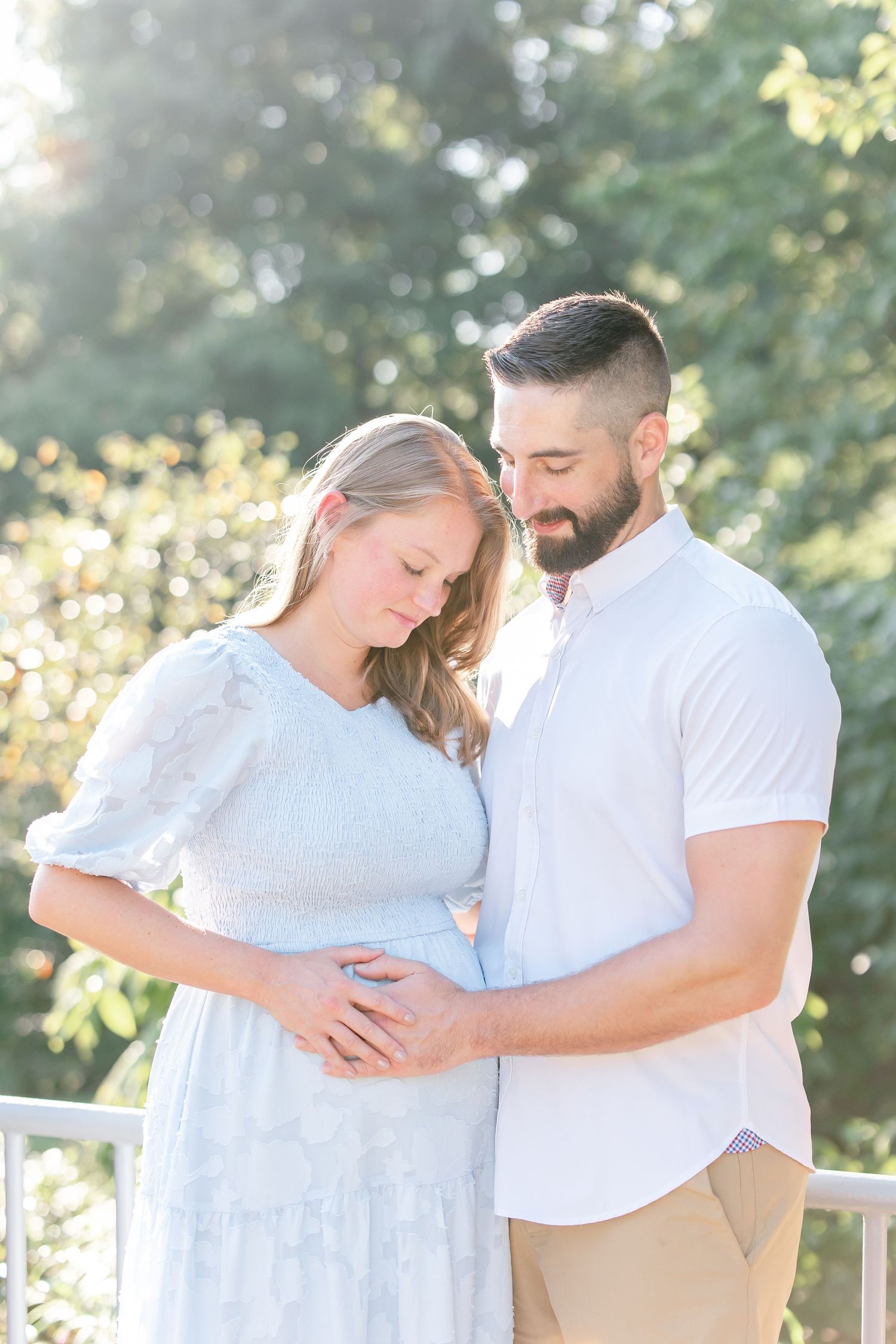 A couple embraces tenderly in a romantic outdoor photoshoot wearing white and light colors.