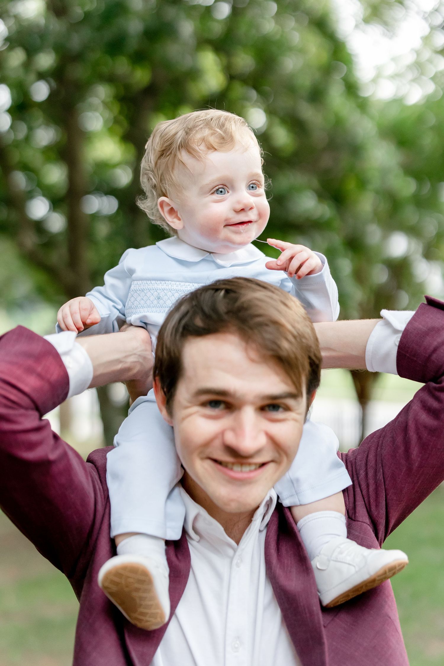 A playful sequence showing a baby being lifted up in an outdoor setting with soft bokeh effect.