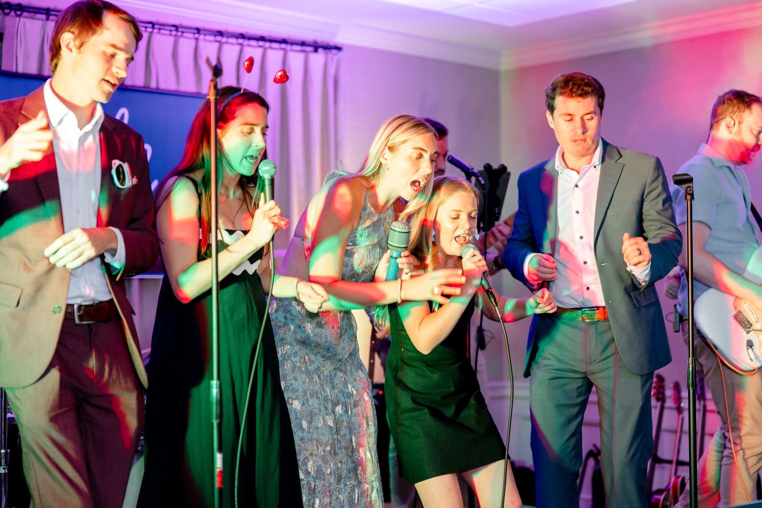 Dance party with colorful purple lighting and people dancing in formal attire.
