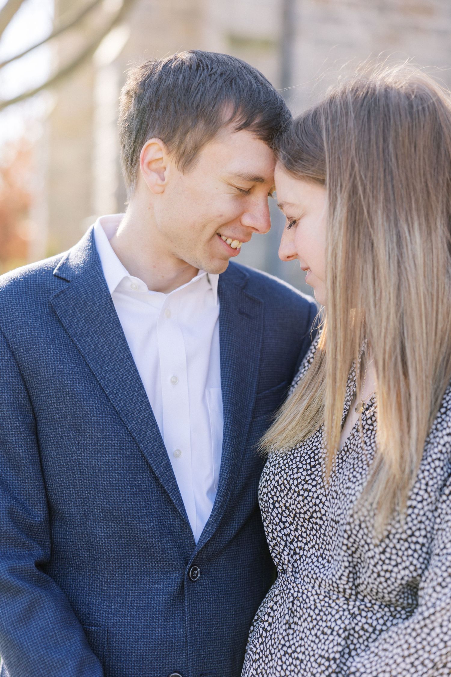 A romantic couple shares an intimate moment in soft sunlight while wearing coordinated formal attire.