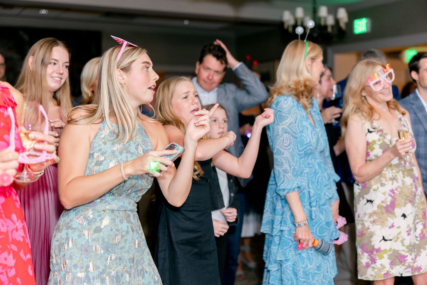 People dancing and celebrating at an indoor party with blue lighting and festive atmosphere.
