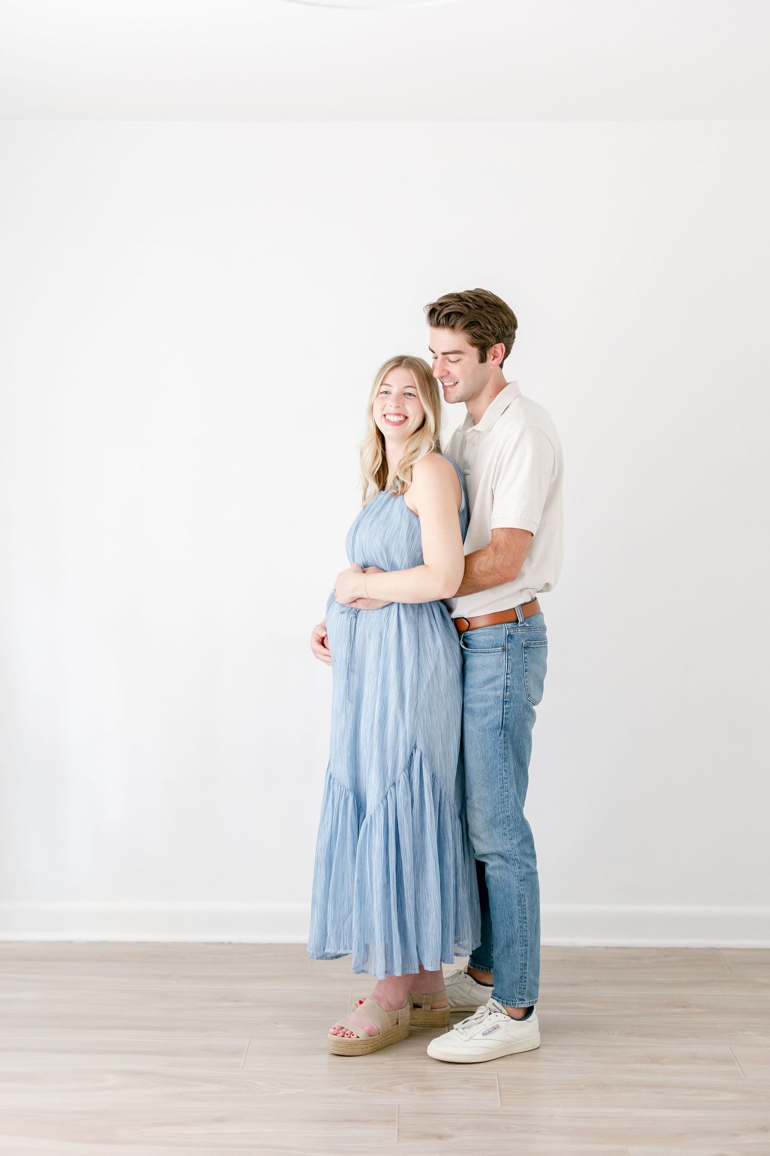 A couple shares an intimate moment together while dancing in a bright white studio setting.