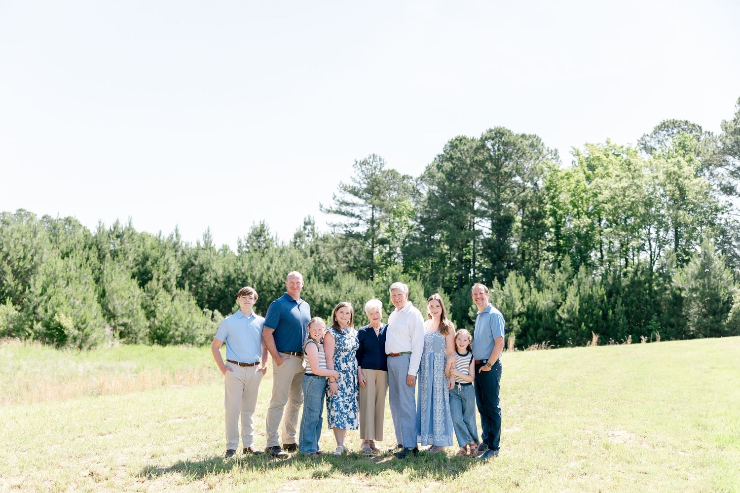 A group of people in coordinated blue and white outfits standing together on a grassy field with trees in the background.