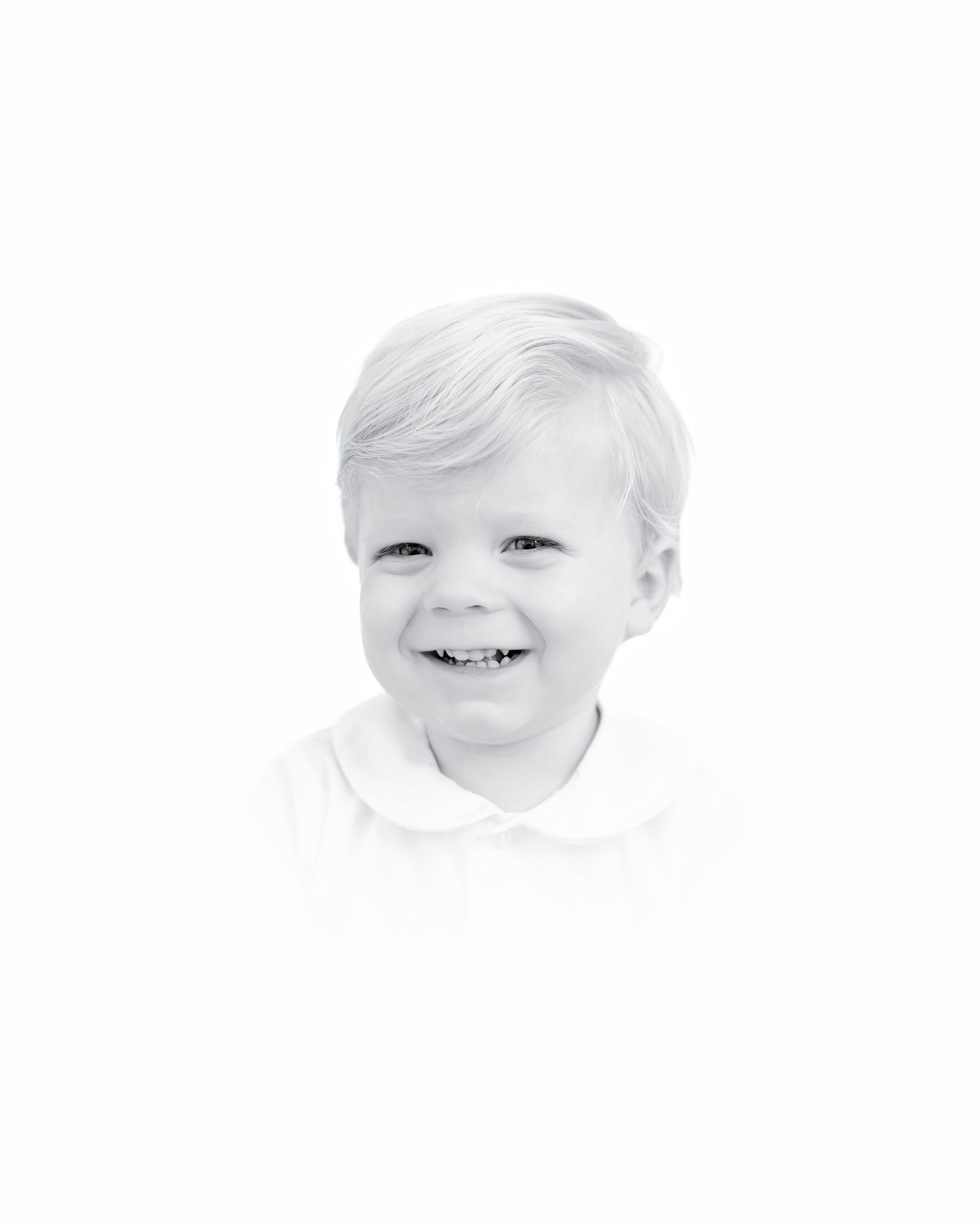 A black and white portrait capturing a joyful smile and bright eyes in a high-key photograph.