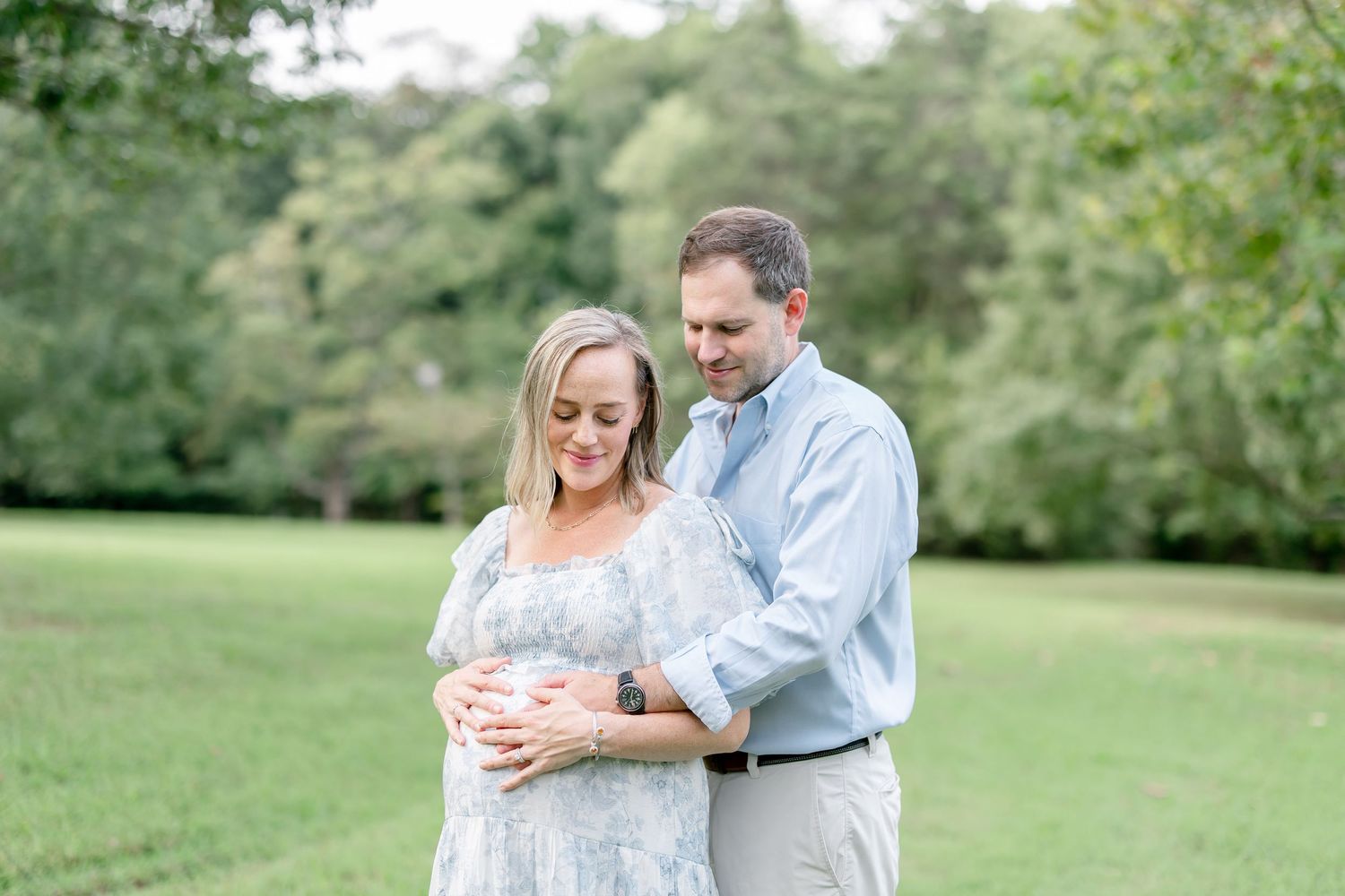 People embrace during an intimate outdoor photo session in a lush green garden setting.