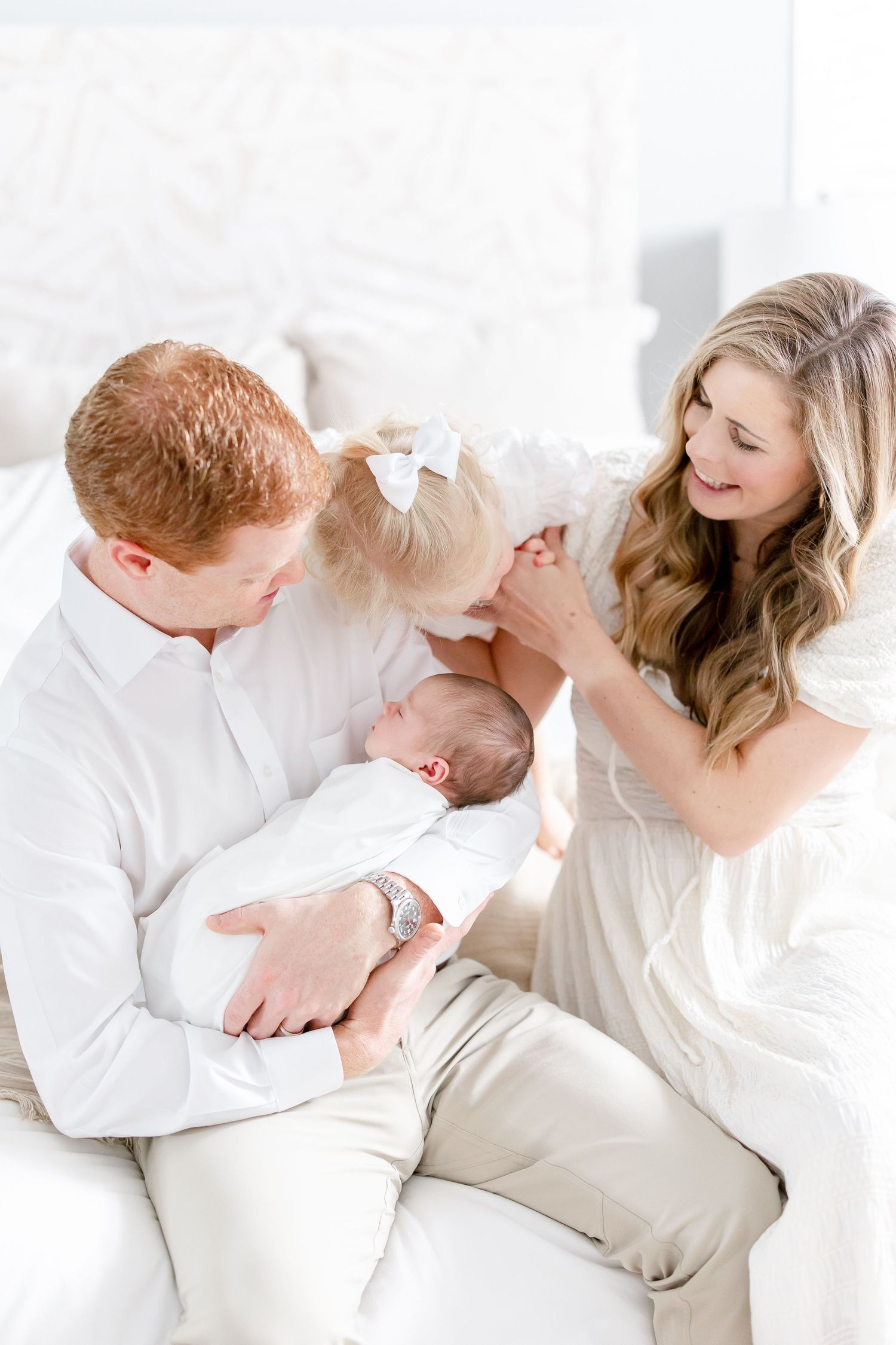 A family shares an intimate moment together on white furniture.