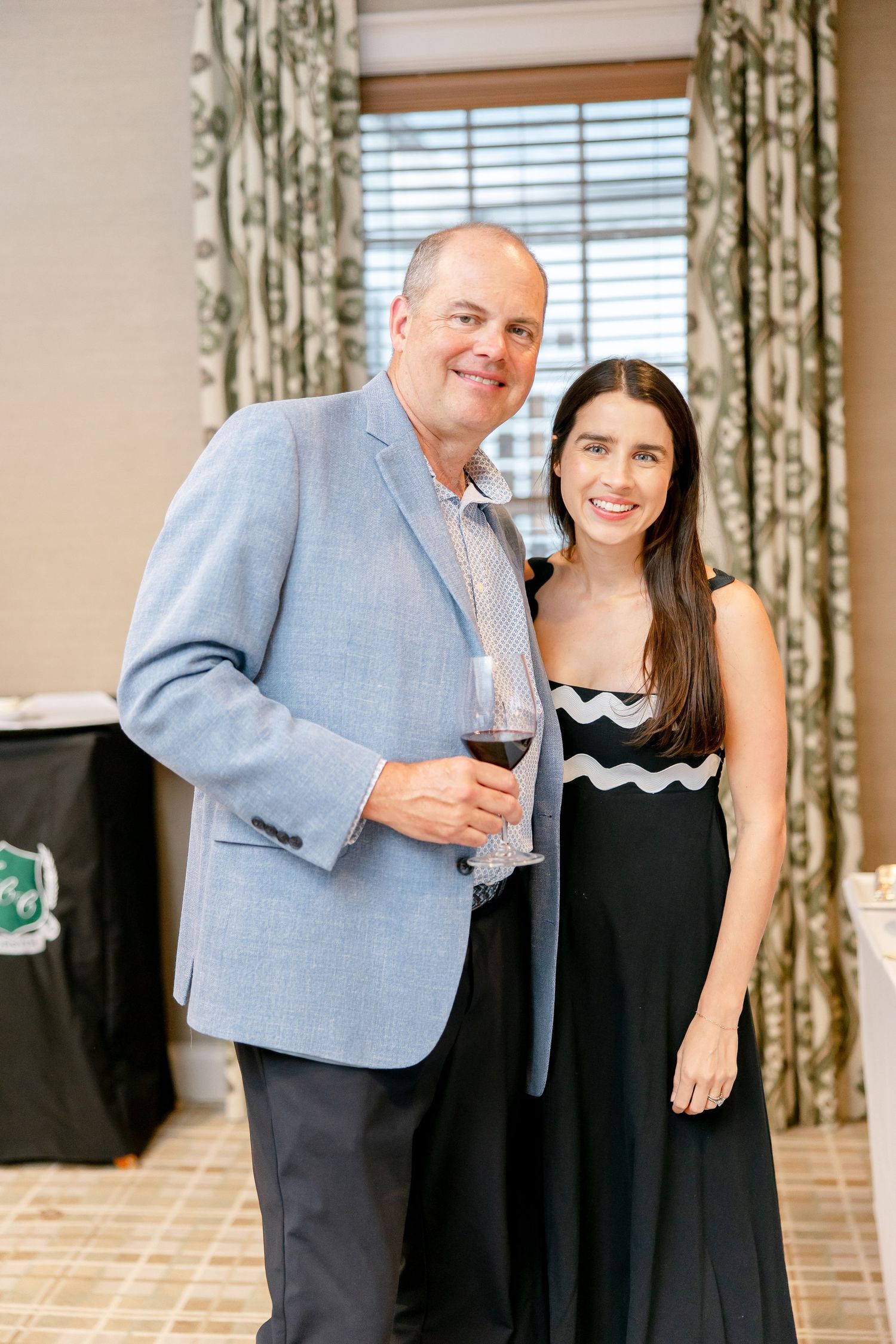 People in formal attire sharing wine and conversation at an upscale event.