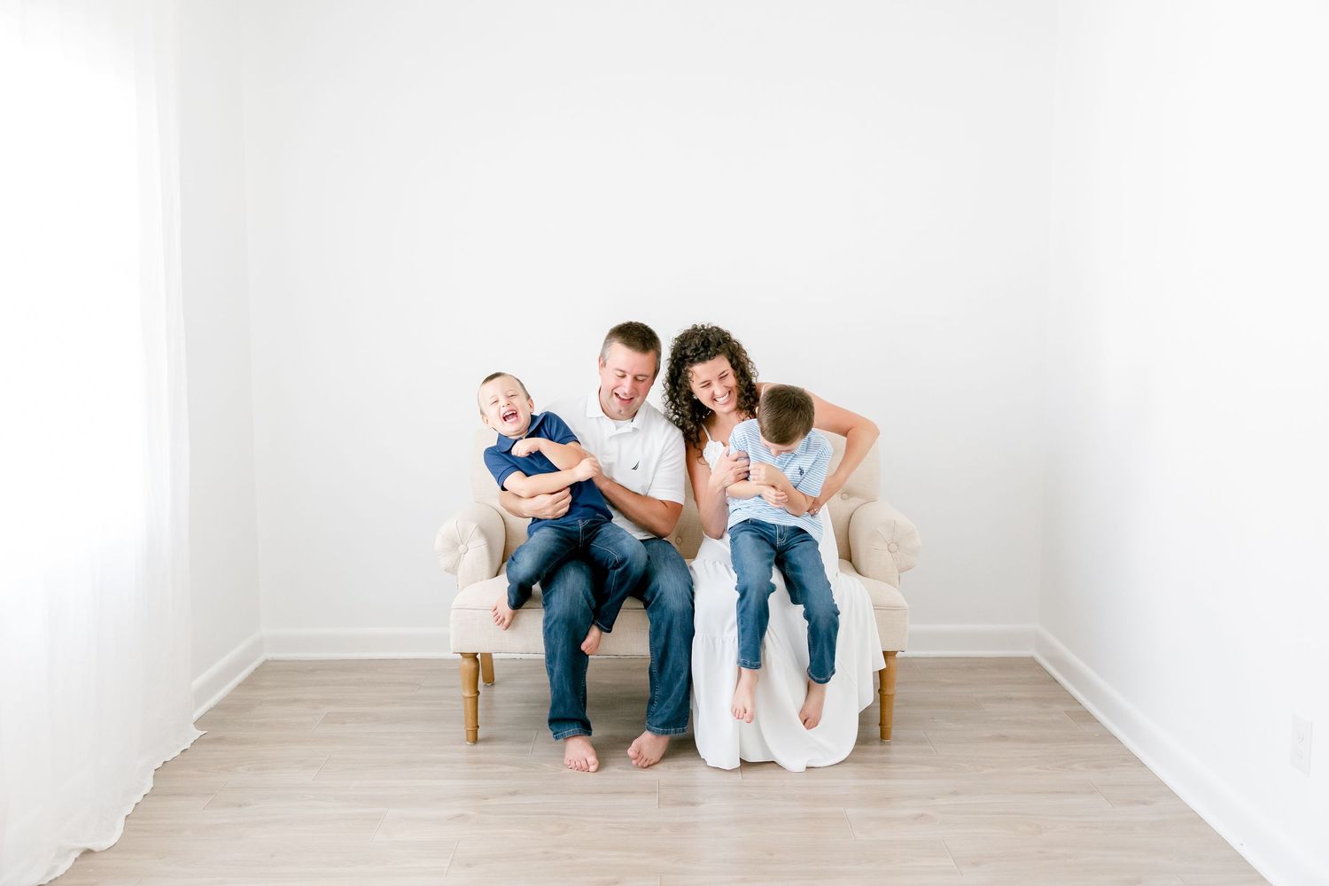 Group sitting comfortably on white floor in minimalist studio wearing casual clothing.