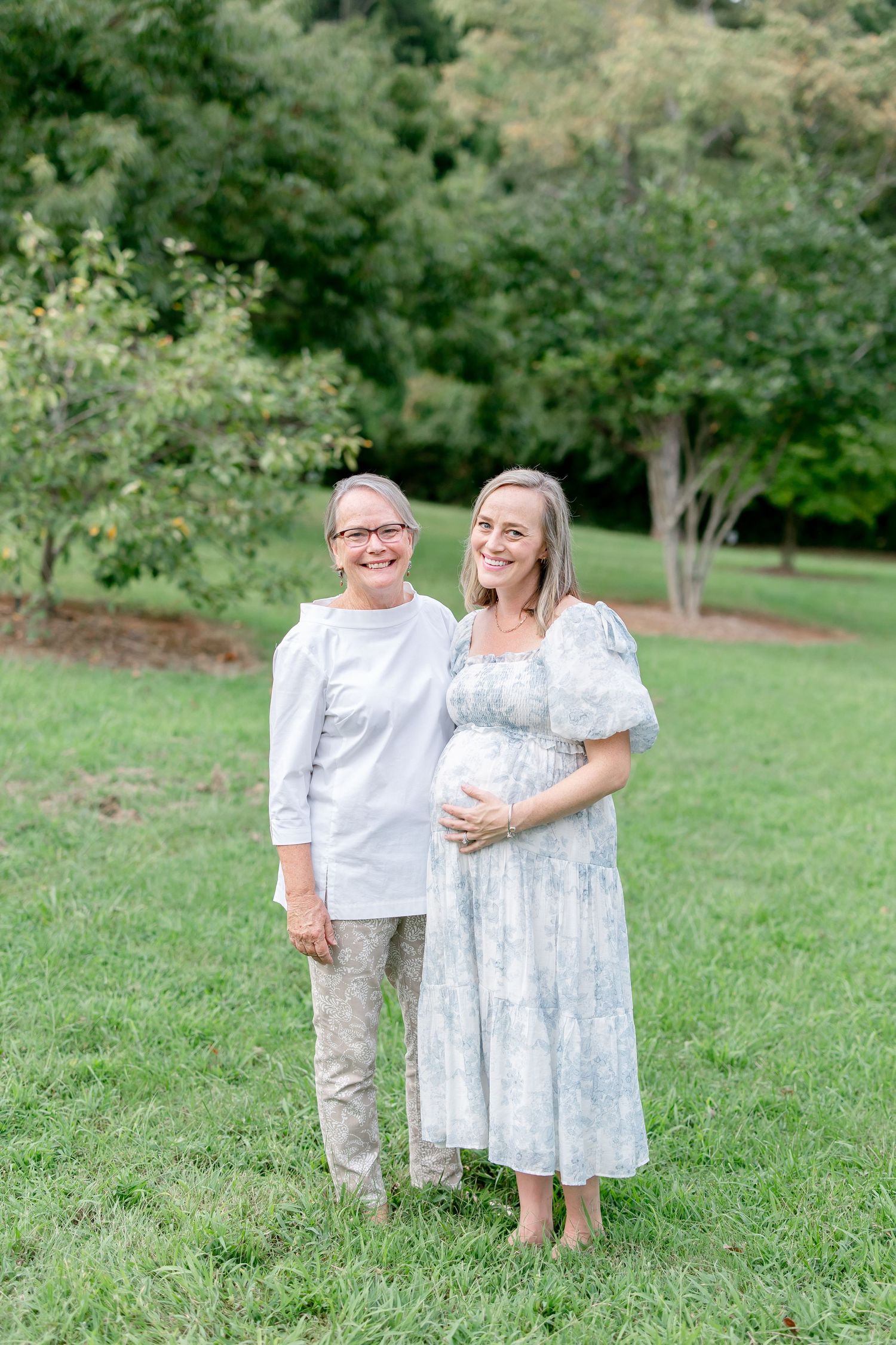Family members pose together on a grassy slope with trees in the background.