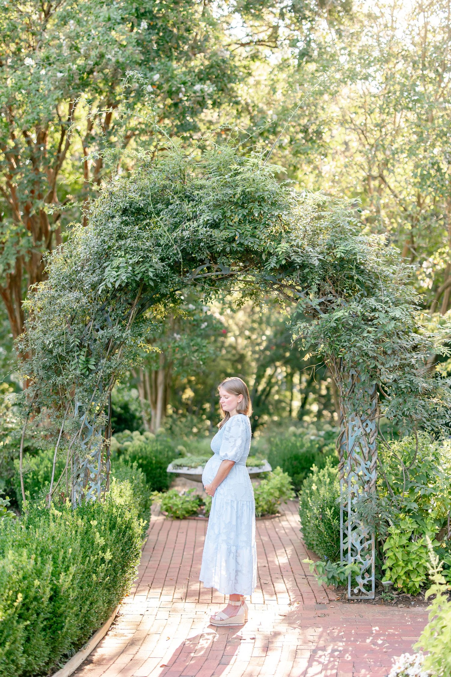 Couple enjoys tender moments under a garden archway surrounded by green foliage.