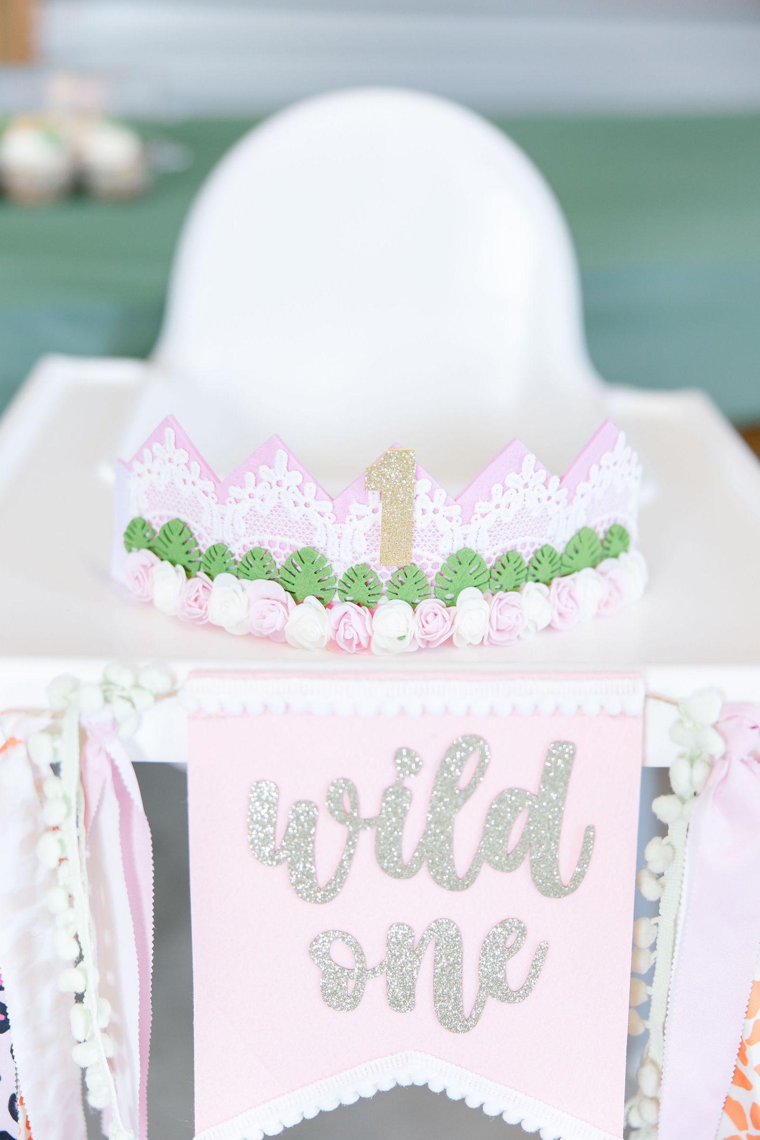 Pink and silver 'Wild One' banner with lace crown decoration for first birthday party.