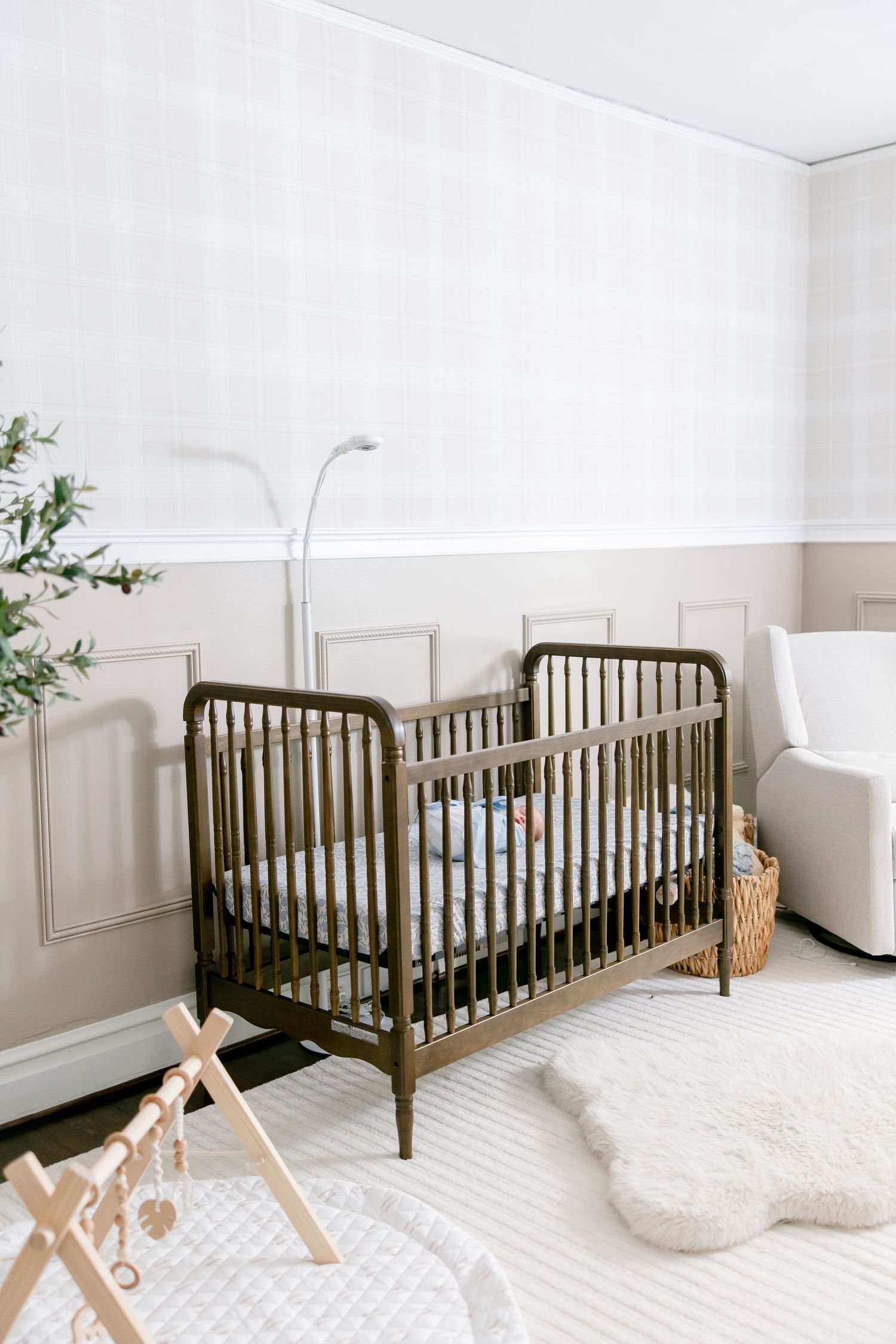 Minimalist nursery features dark wood crib against white walls with scattered decorative accents.