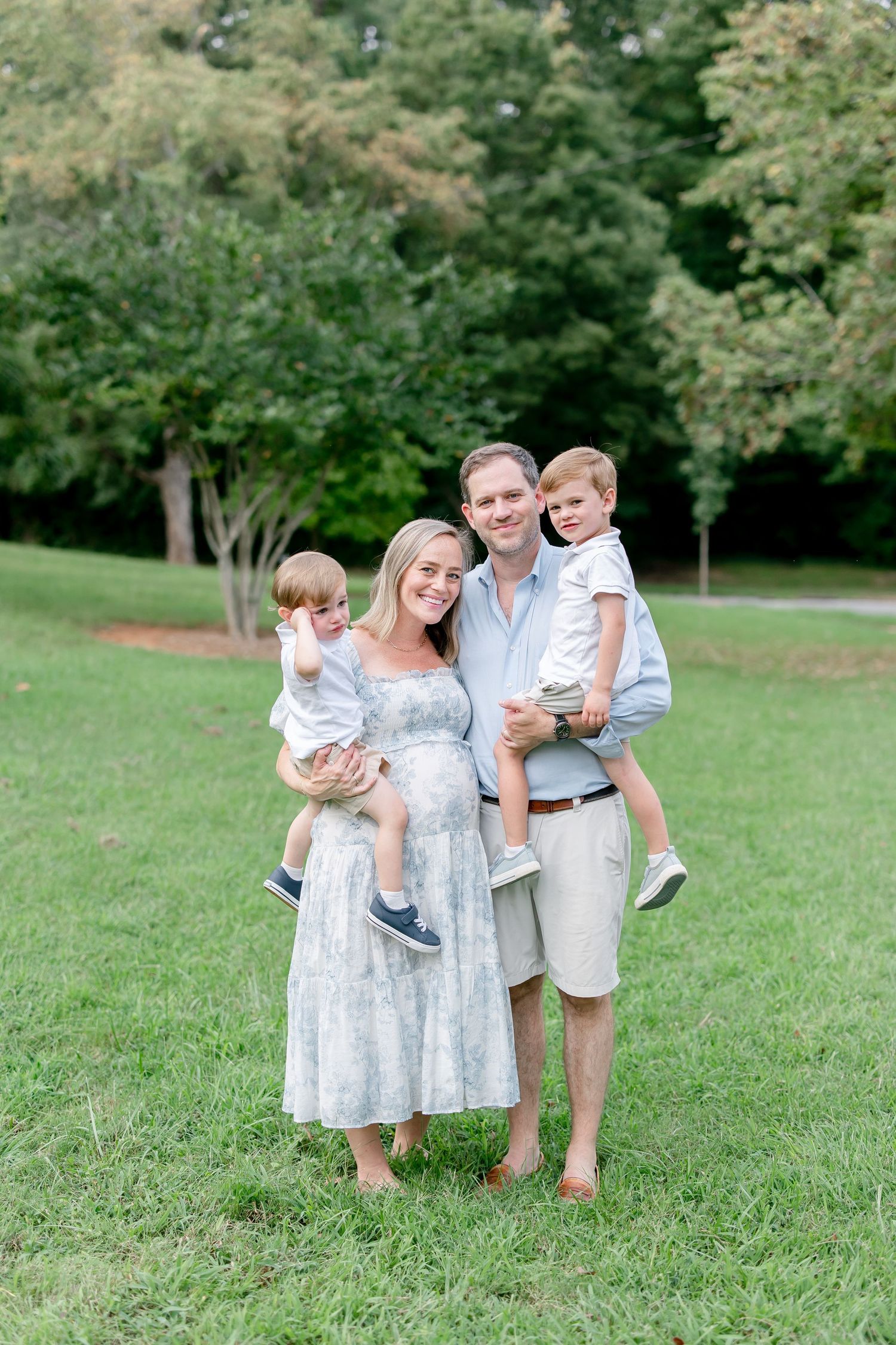 Family portrait session showing group in matching blue and white outfits standing together on grass.
