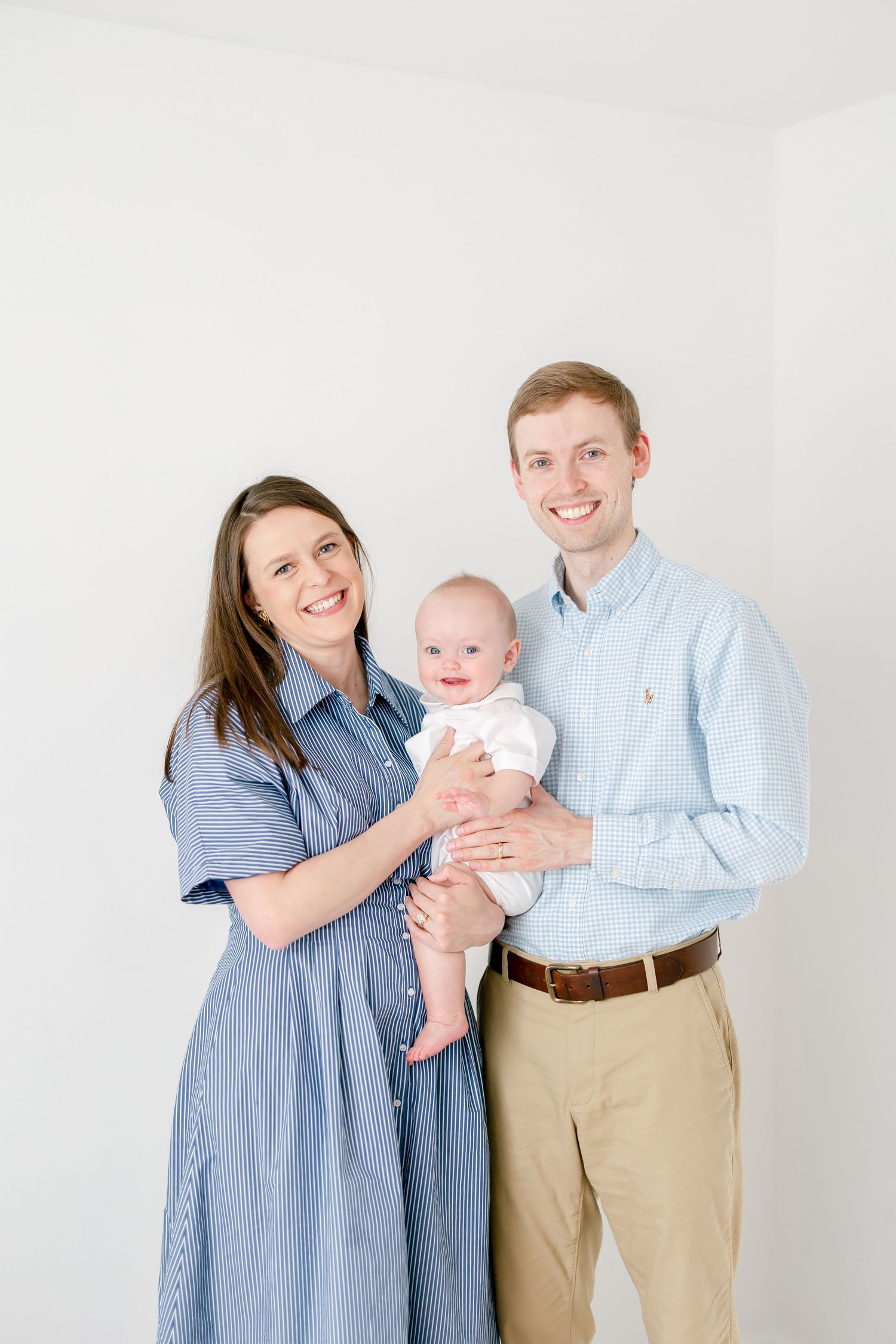 Family wearing coordinating blue outfits posing together with baby for portrait.