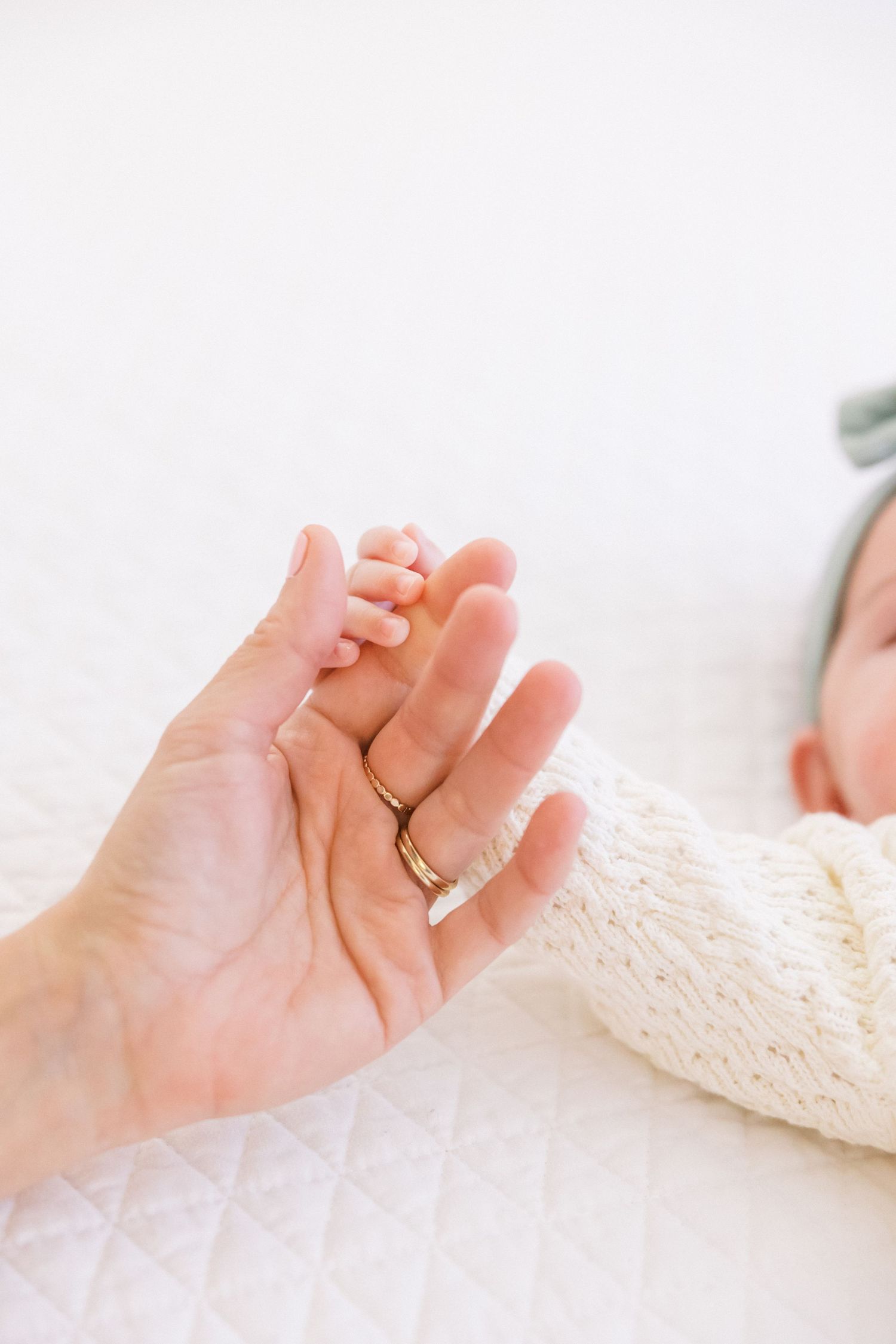 Close up view of tiny newborn baby feet resting on adult's palm.