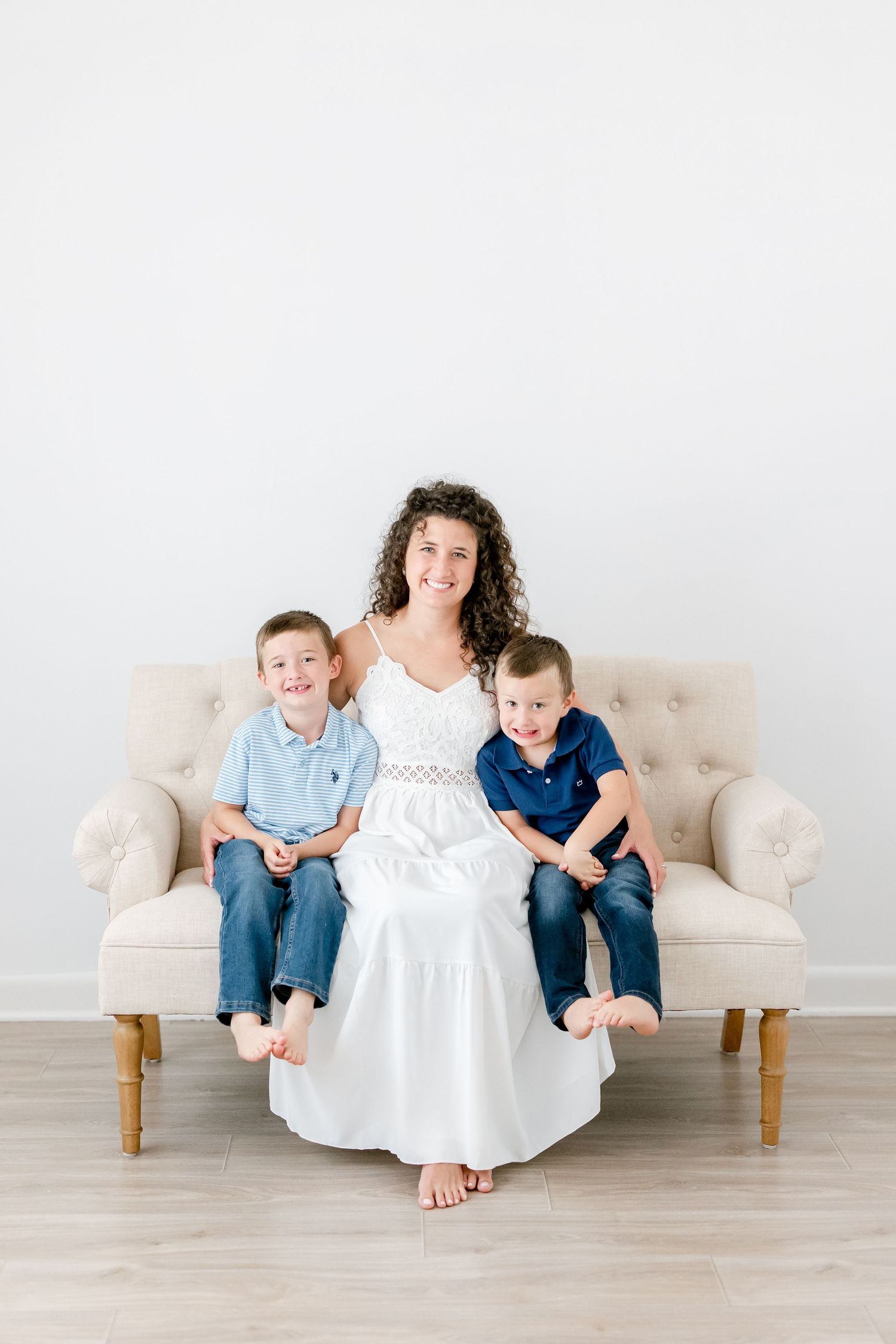 Family group sits together on beige sofa wearing coordinated blue and white outfits.