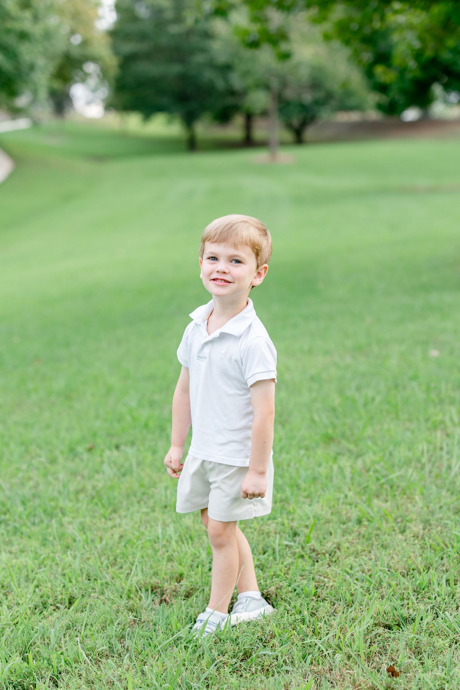 Four sequential photos showing a child in a white shirt playing and sitting on green grass in a park setting.