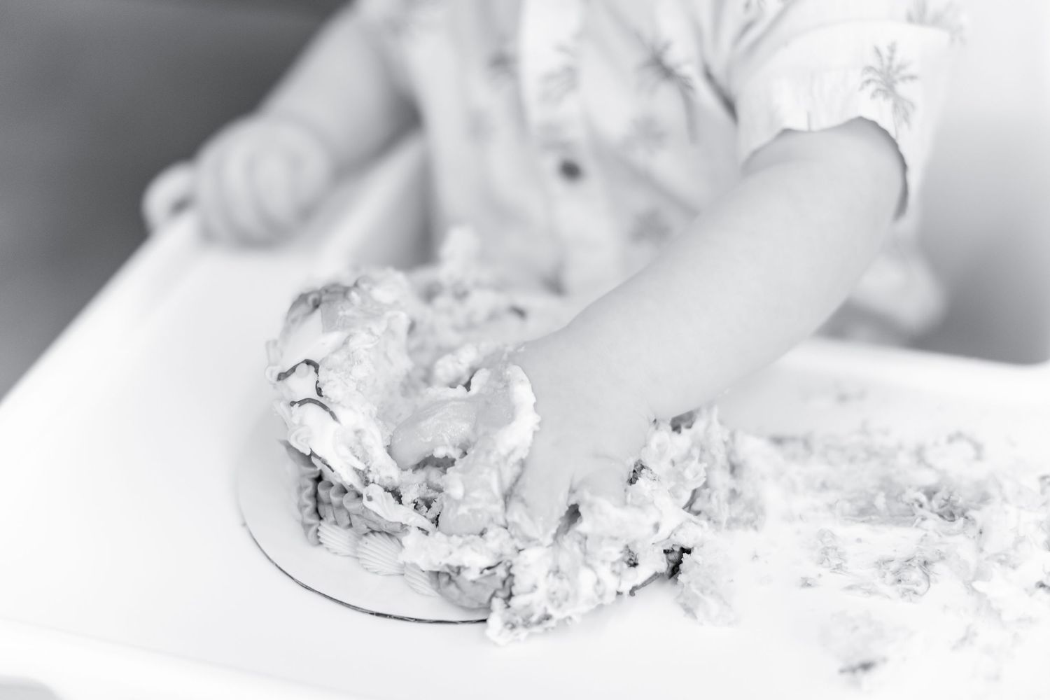 Close-up of small hands playing with flour or dough on a white surface.