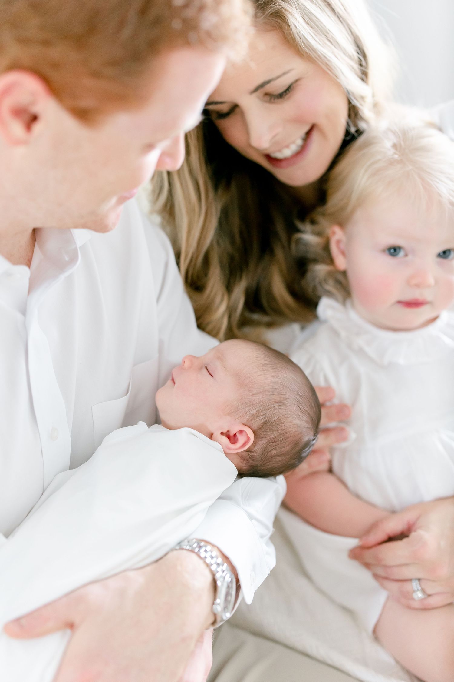 An intimate family moment captured in soft natural light with everyone dressed in white.