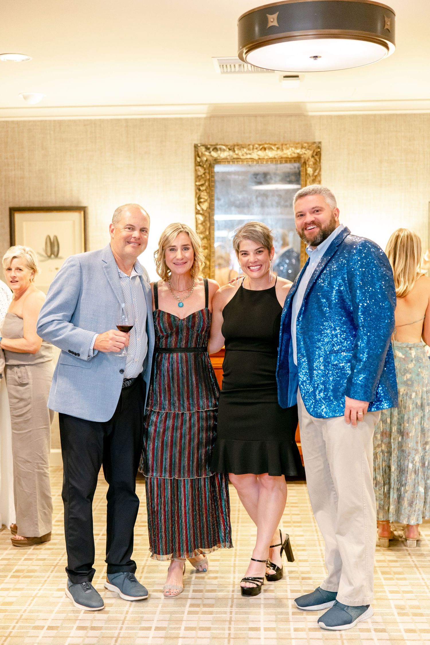 A group of people at a formal event, with someone wearing a sparkly blue jacket amongst the crowd.