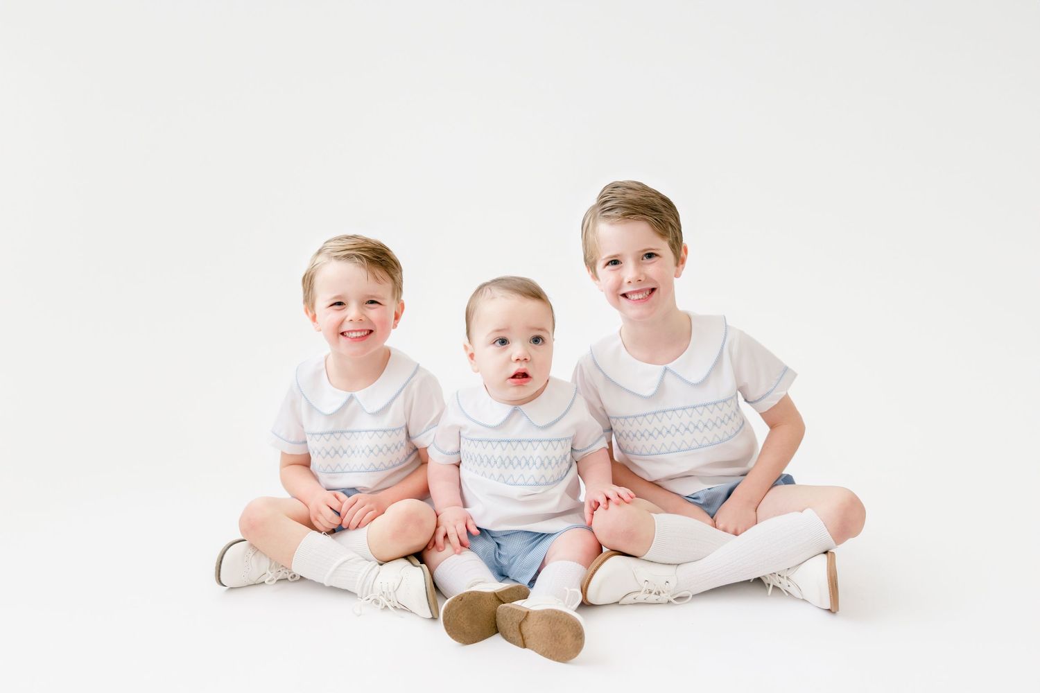 Three young children in white shirts sitting together in a progression of poses on a white background.