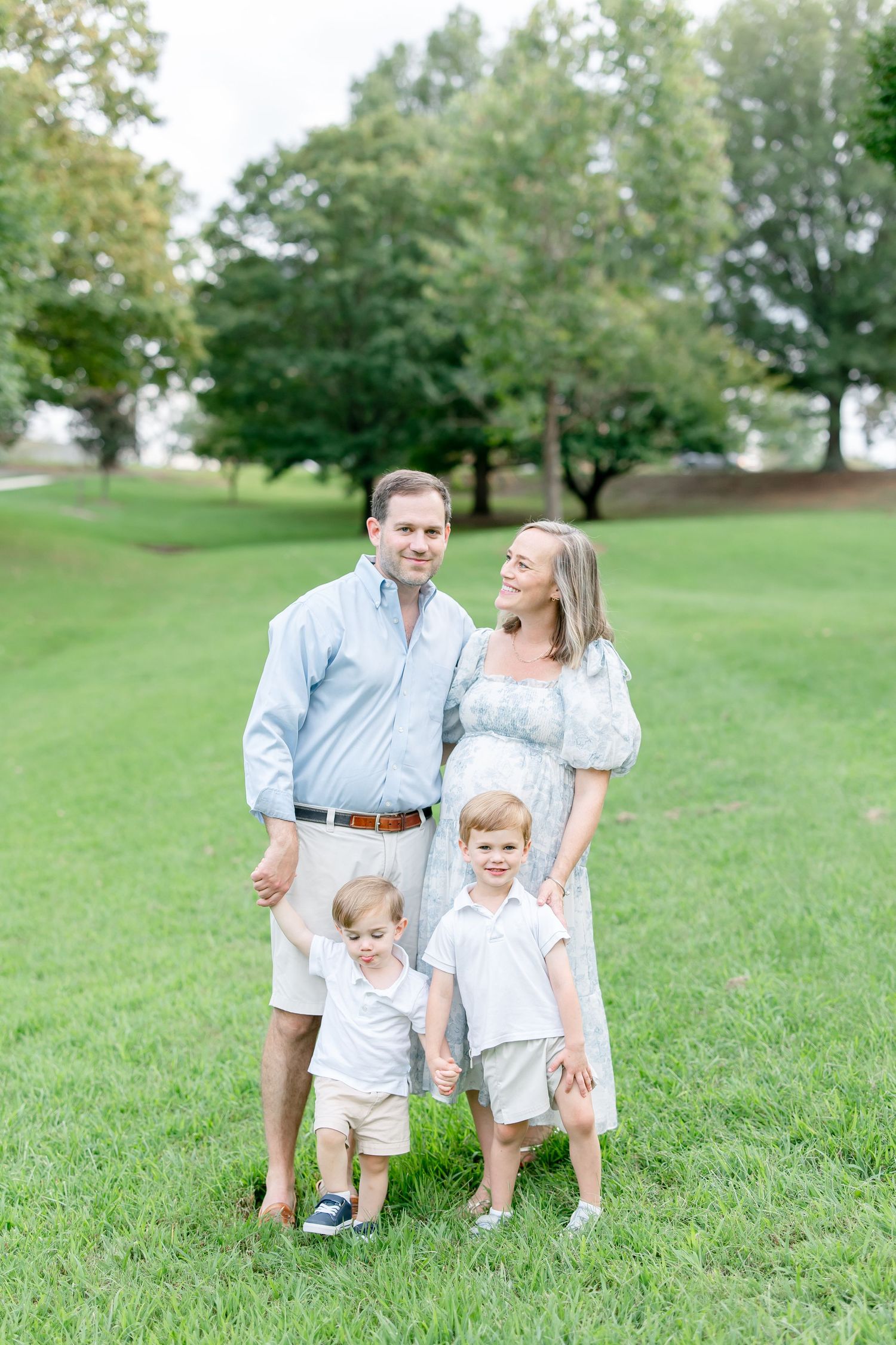 A family spending time together outdoors on a grassy hill during a summer day.
