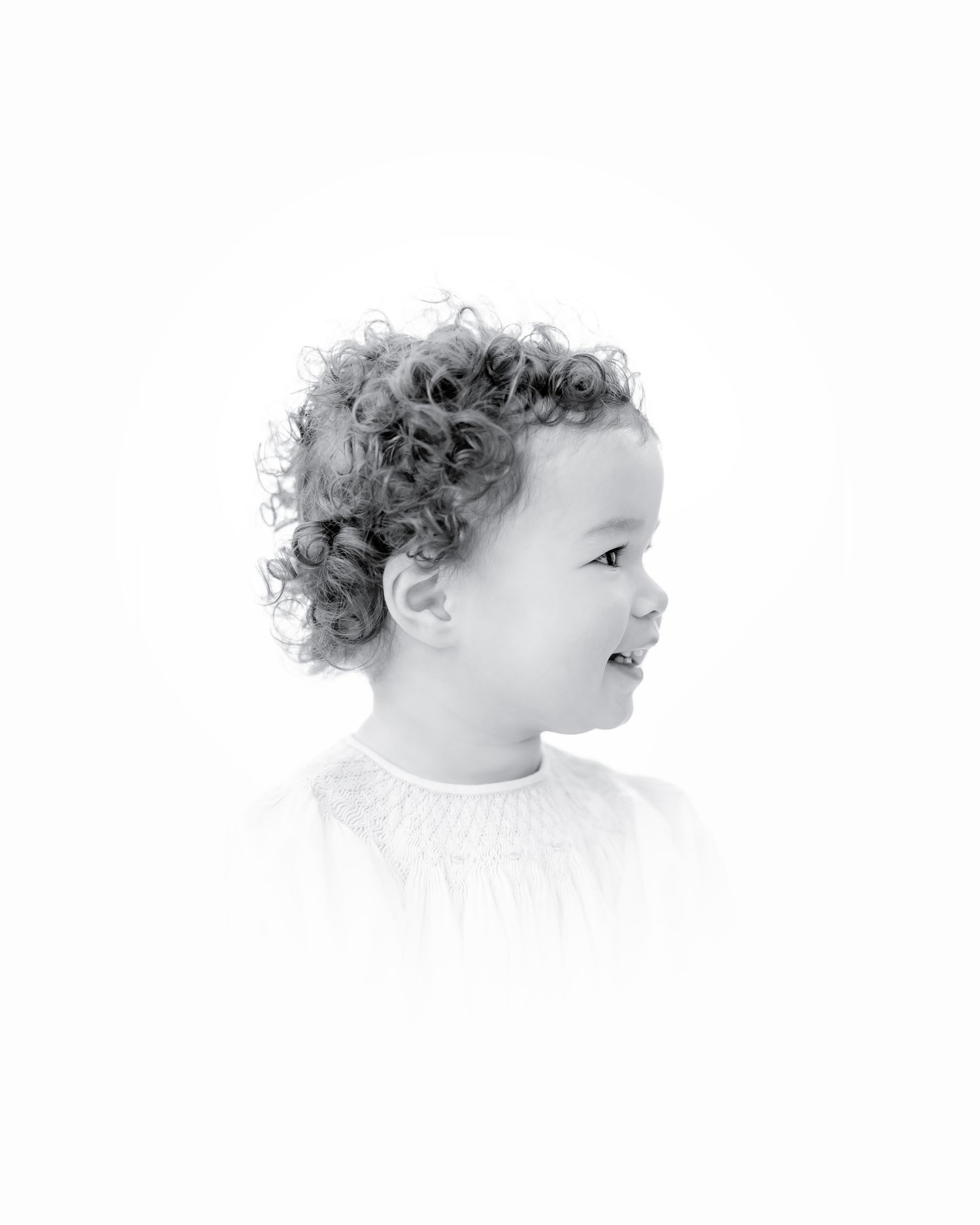 A side profile portrait of a young child with curly hair in black and white style.