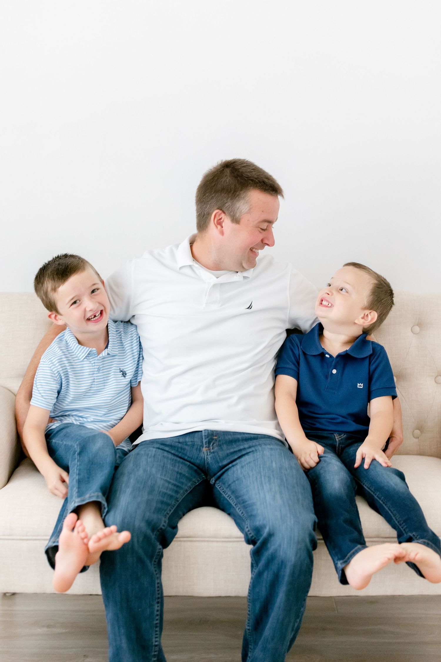 Playful family moment captured on couch with matching blue and white outfits.