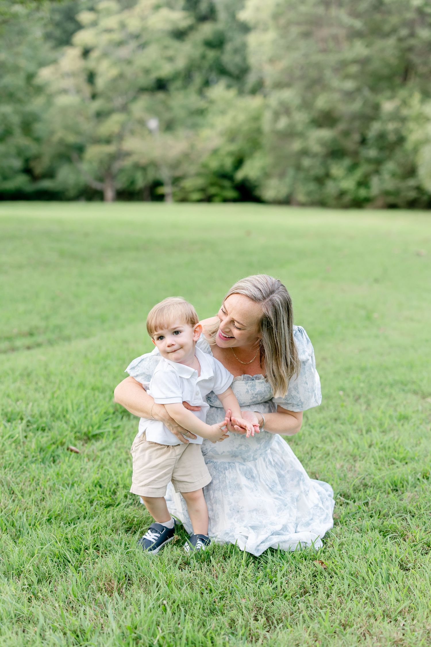 Playful outdoor family moment captured on a sunny day in a green park setting.