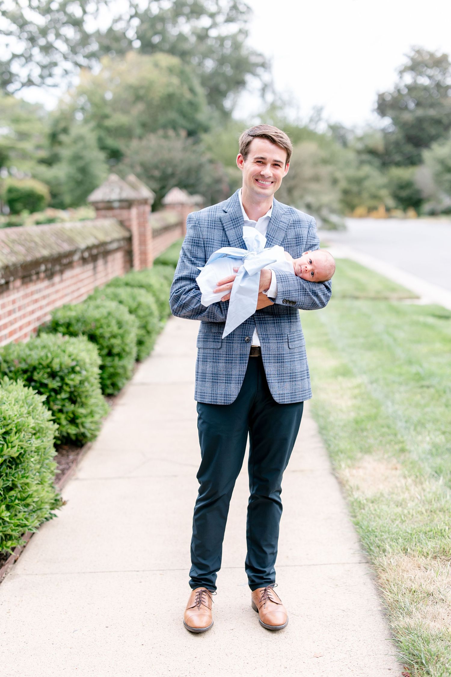 Full length portrait series on garden path showing man holding infant.