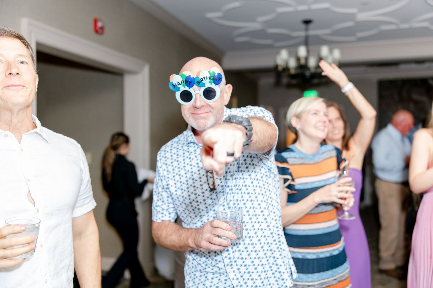 A festive crowd enjoying a dance party with colorful lights and decorations at a wedding reception.