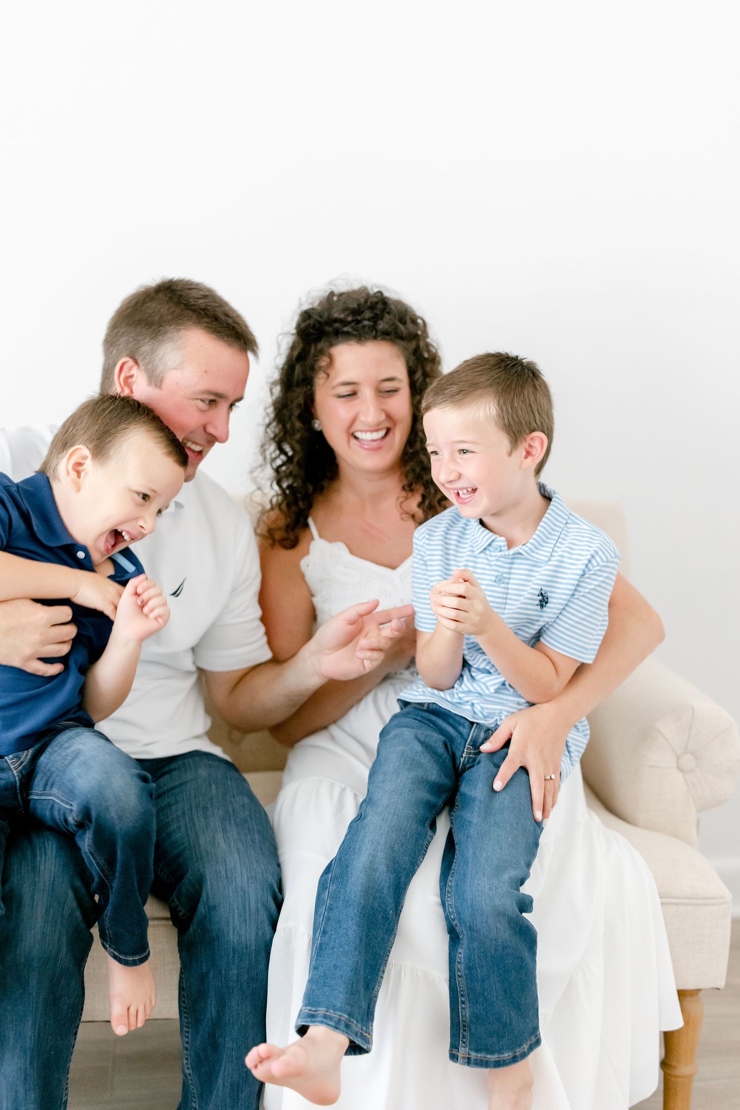 Candid family portraits showing intimate moments of laughter and connection on a light beige sofa.