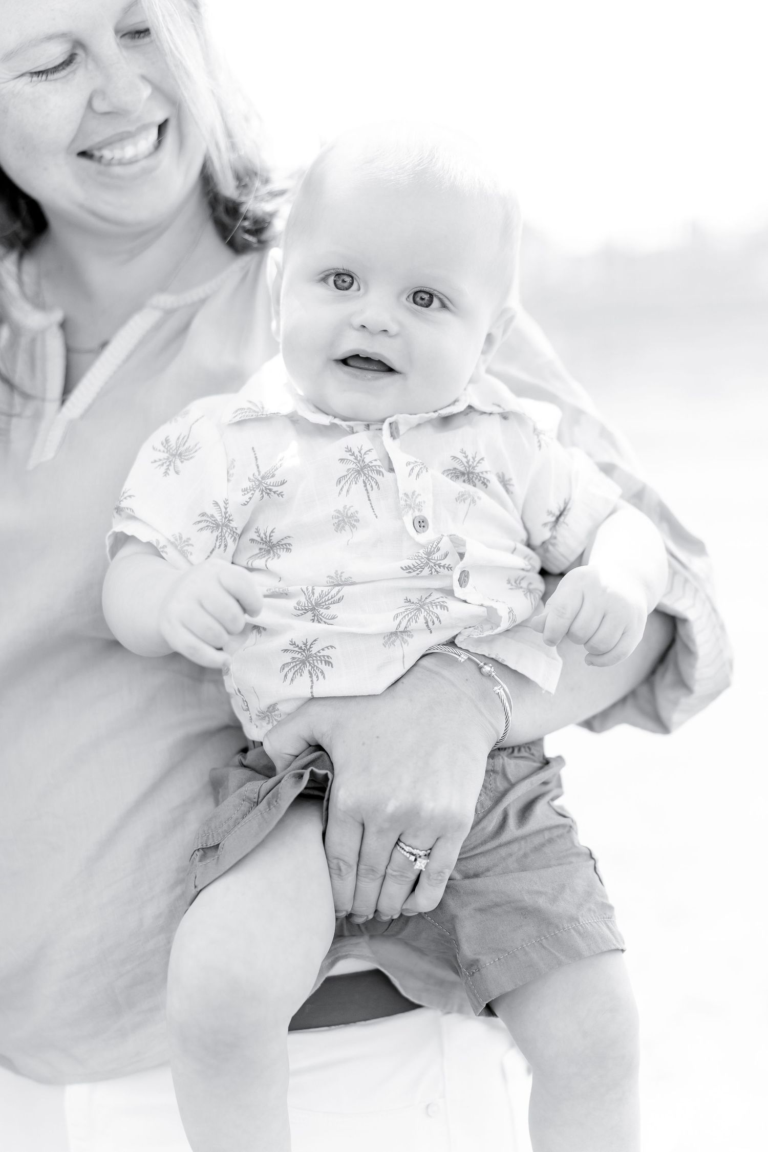 Black and white portrait of happy baby in patterned outfit.