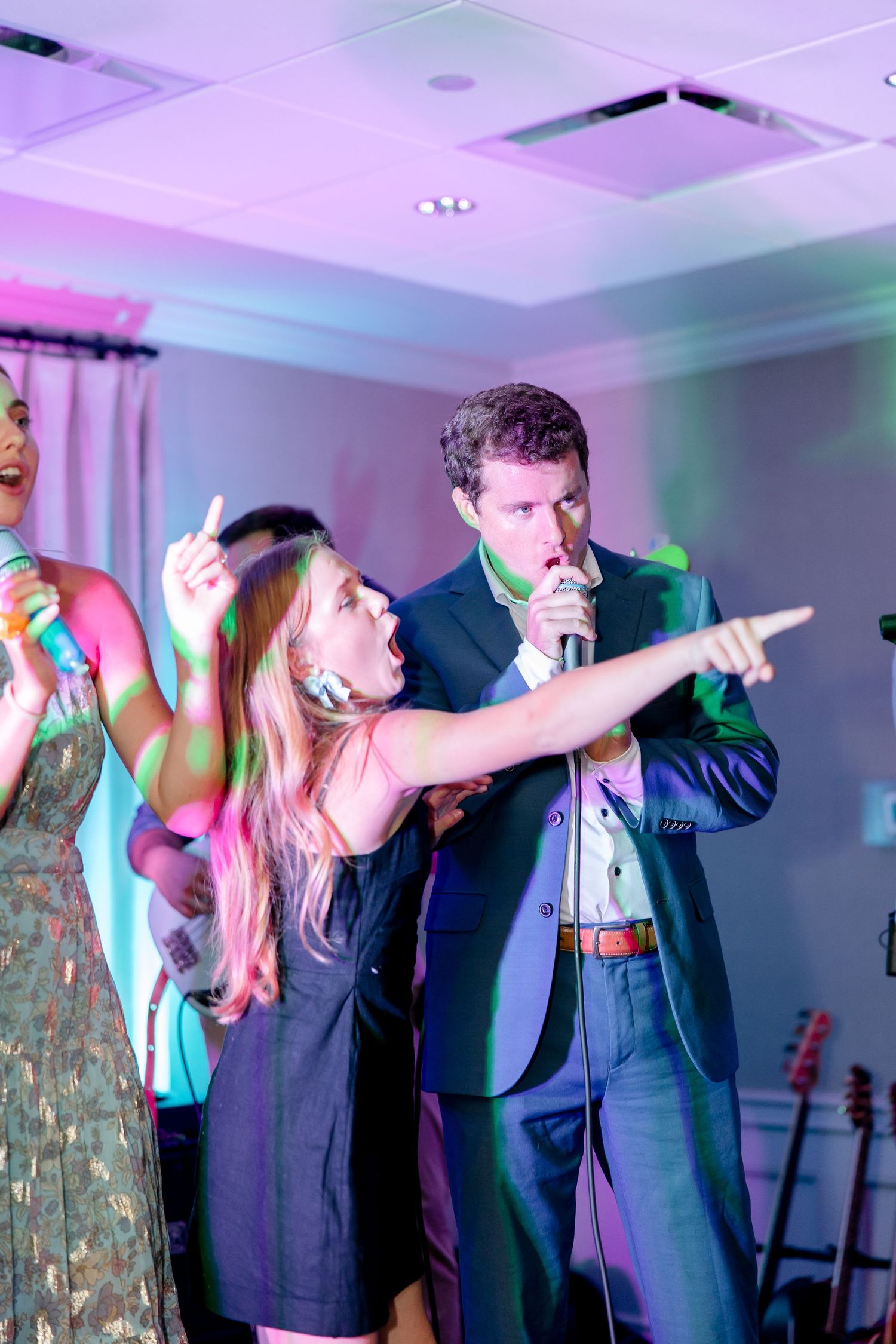 Performers singing and gesturing dramatically during karaoke performance with colored stage lighting.