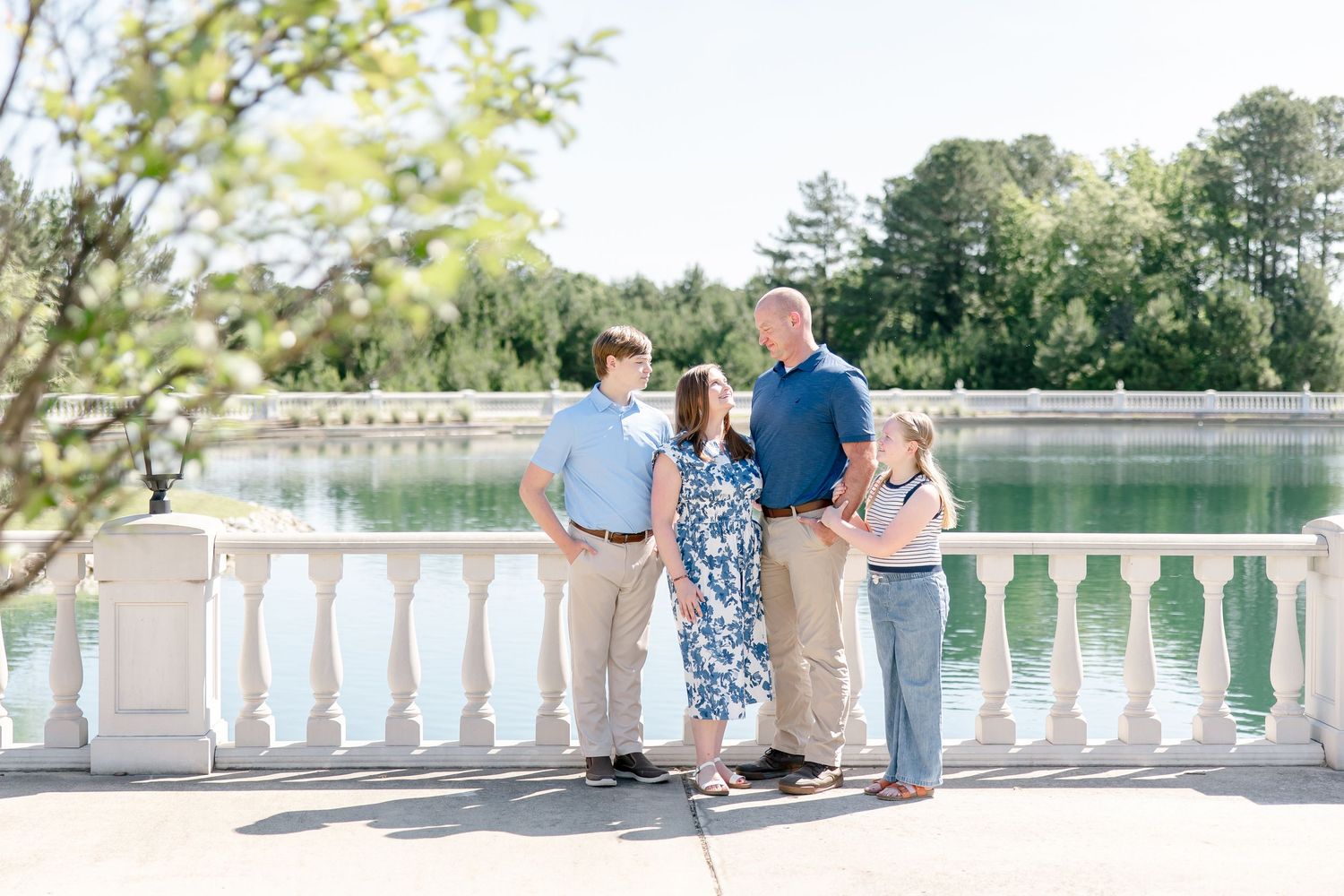 A split-panel montage of four photos showing a romantic couple sitting on a stone balustrade by a lake in summer.